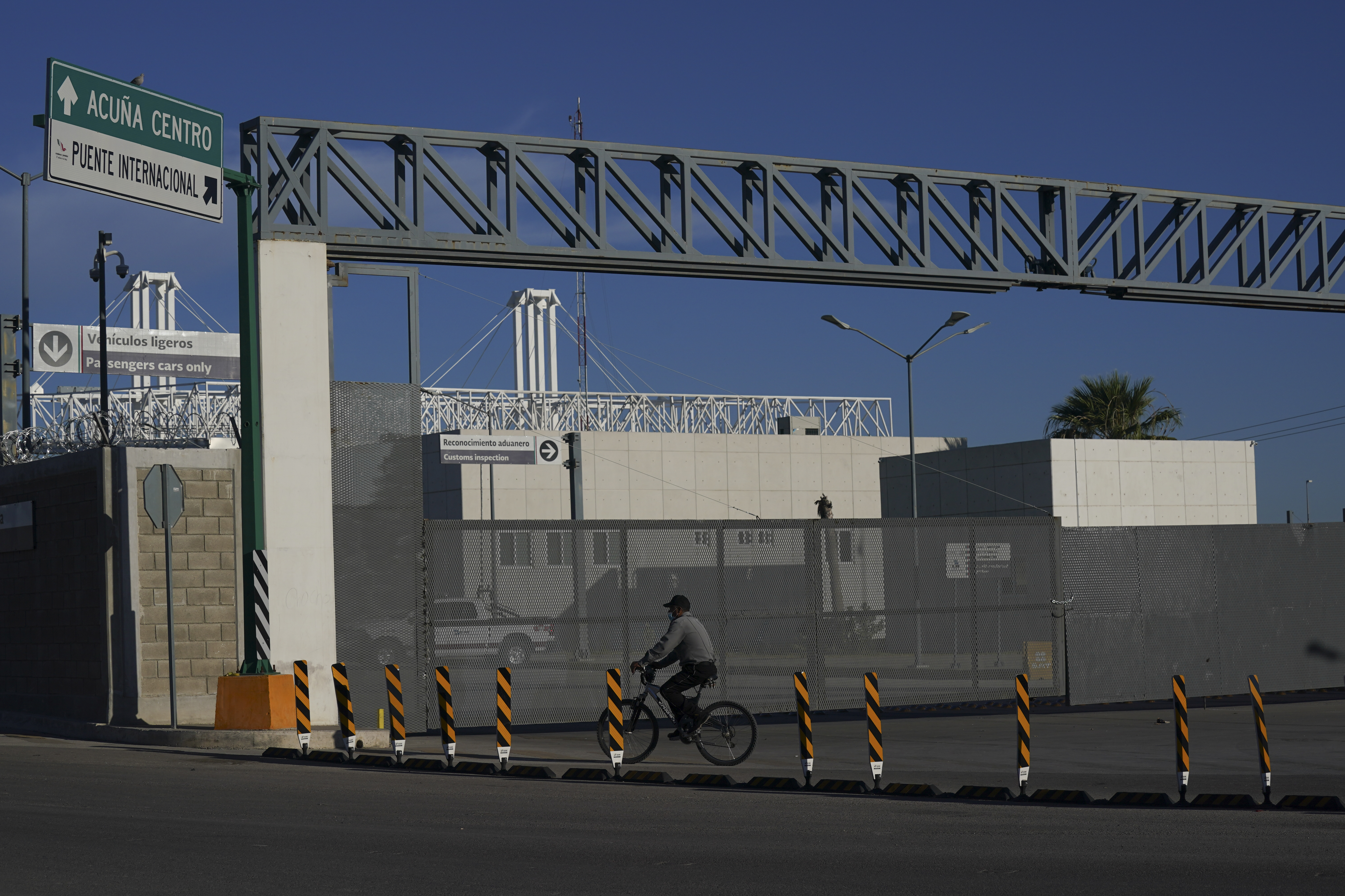 A man rides his bike past the closed main entrance of the international border bridge that connects the cities of Del Rio, Texas and Ciudad Acuna, Mexico, Friday, Sept. 24, 2021. (AP Photo/Fernando Llano)