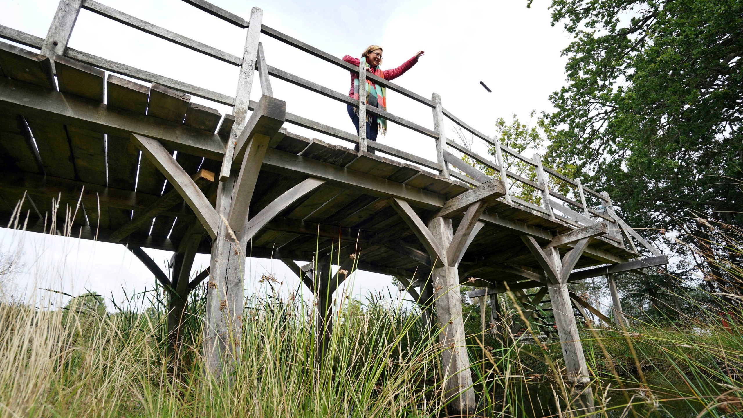 Silke Lohmann of Summers Place Auctions stands on the original Poohsticks Bridge from Ashdown Forest, featured in A.A. Milne's Winnie the Pooh books and E.H. Shepard's illustrations, near its original location in Tonbridge, Kent, England, Thursday, Sept. 30, 2021. (Gareth Fuller/PA via AP)