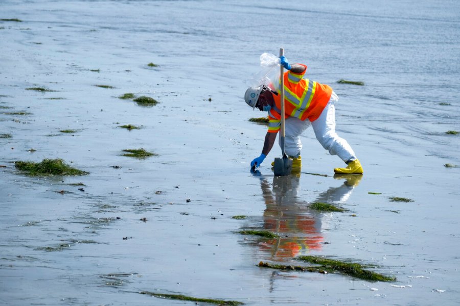 A worker in protective suit cleans the contaminated beach after an oil spill in Newport Beach, Calif., on Wednesday, Oct. 6, 2021. (AP Photo/Ringo H.W. Chiu)