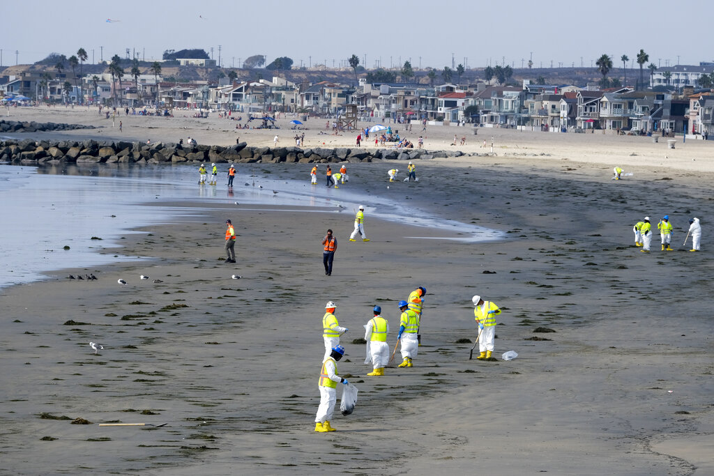 Workers in protective suits clean the contaminated beach after an oil spill, Wednesday, Oct. 6, 2021 in Newport Beach, Calif. (AP Photo/Ringo H.W. Chiu)