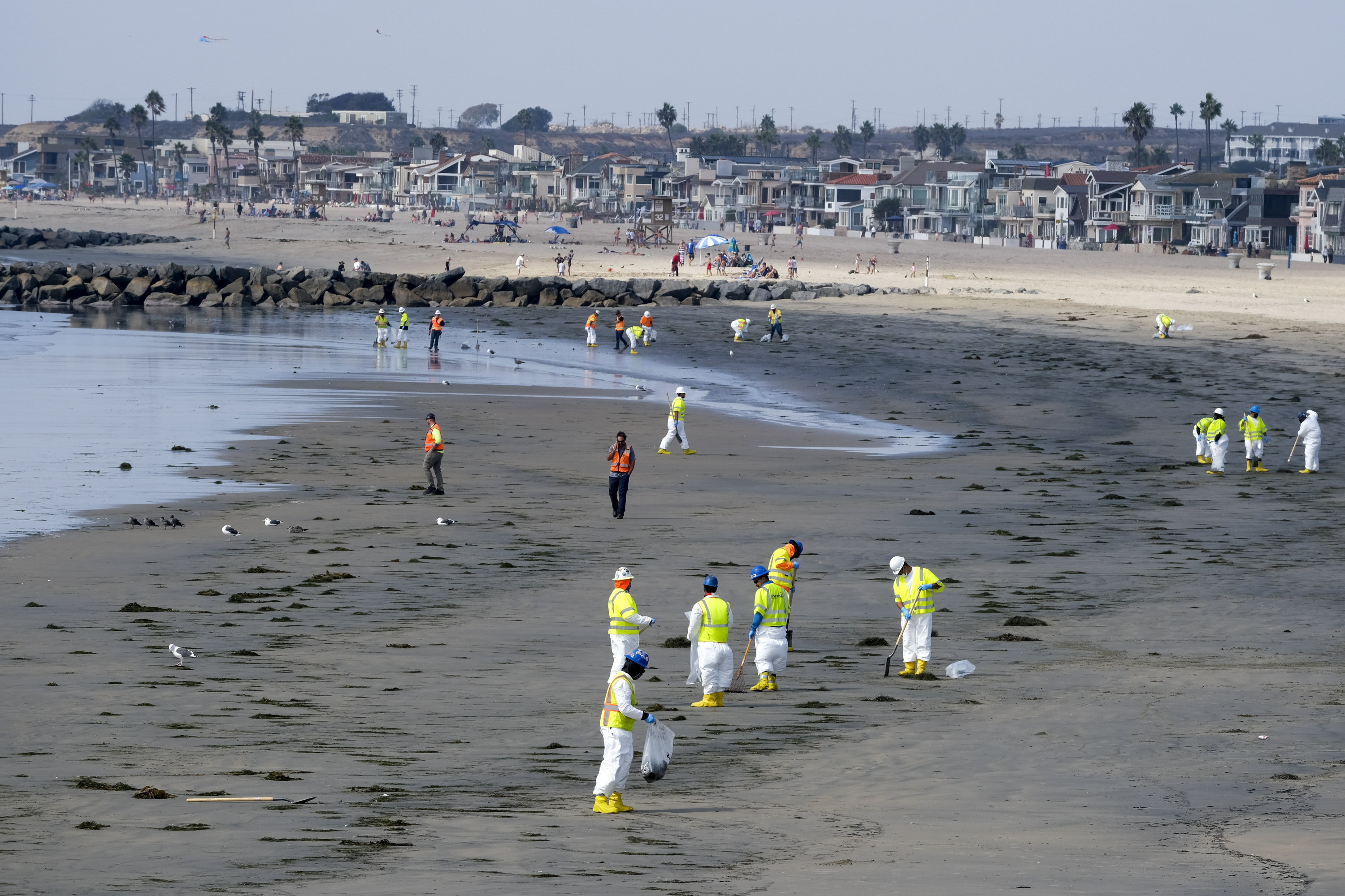 Workers in protective suits clean the contaminated Newport Beach on Oct. 6, 2021, after an oil spill off the coast. (Ringo H.W. Chiu / Associated Press)