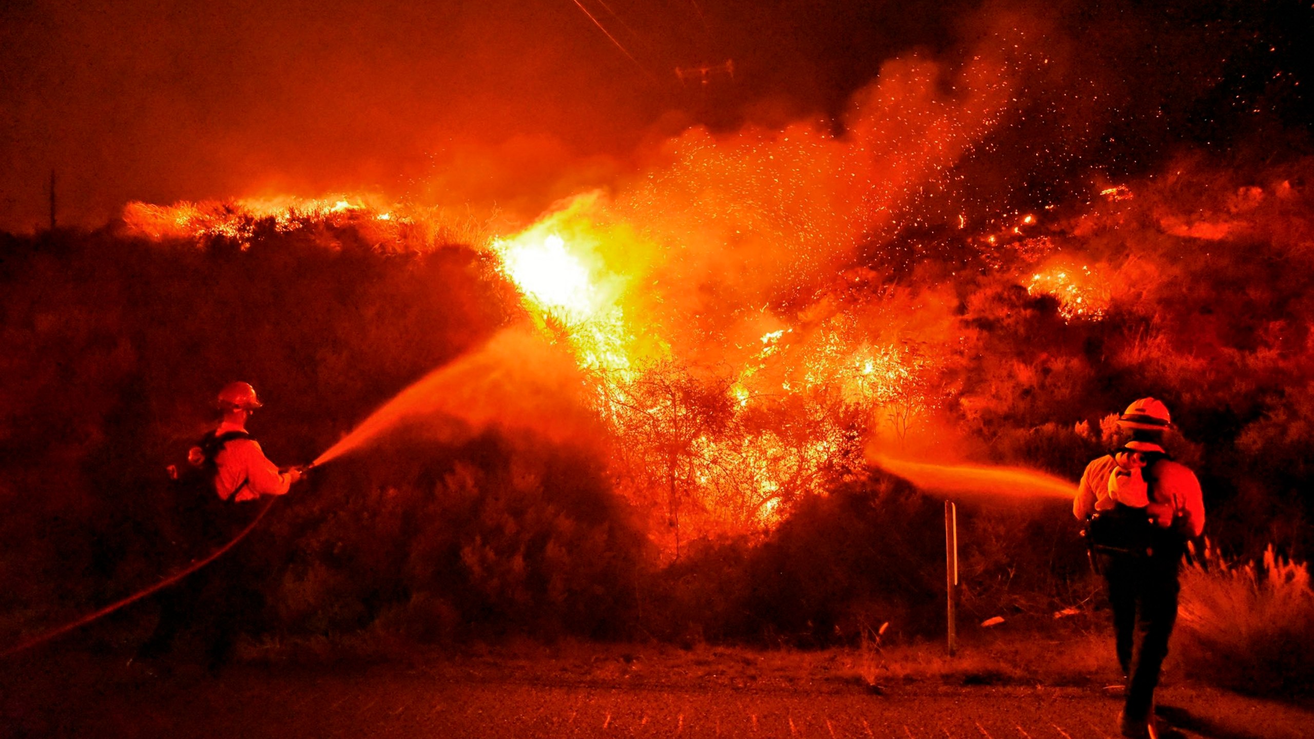 A pair of firefighting dozers, left, cut a line along the western flank of the Alisal Fire near Tajiguas Beach in Santa Barbara County on Oct 12, 2021. (Mike Eliason / Santa Barbara County Fire via Associated Press)