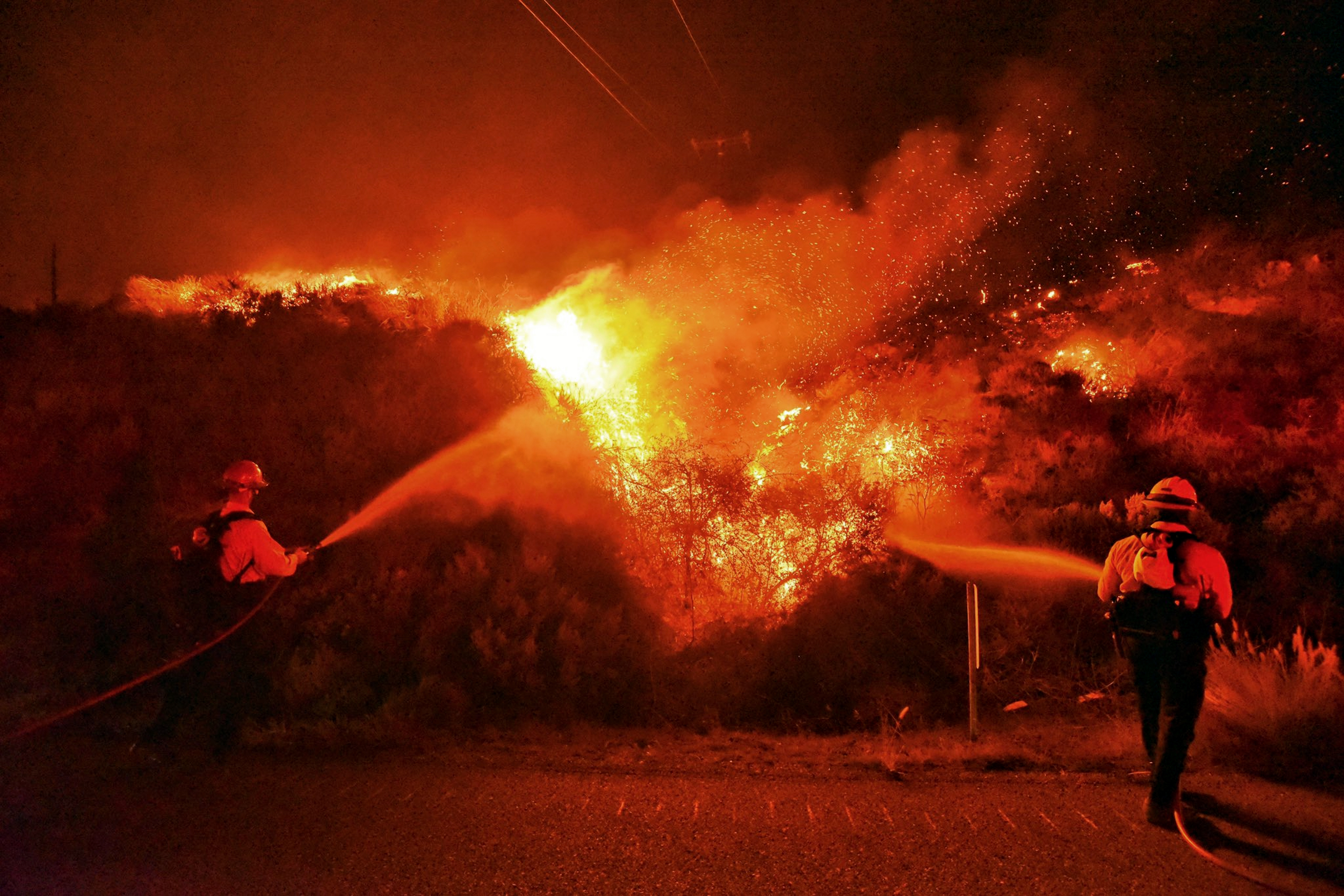 A pair of firefighting dozers, left, cut a line along the western flank of the Alisal Fire near Tajiguas Beach in Santa Barbara County on Oct 12, 2021. (Mike Eliason / Santa Barbara County Fire via Associated Press)