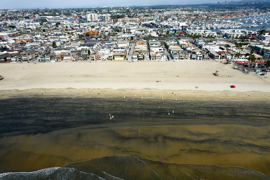 In this Wednesday, Oct.6, 2021 aerial image taken with a drone, workers in protective suits clean the contaminated beach after an oil spill in Newport Beach, Calif. (AP Photo/Ringo H.W. Chiu, File)