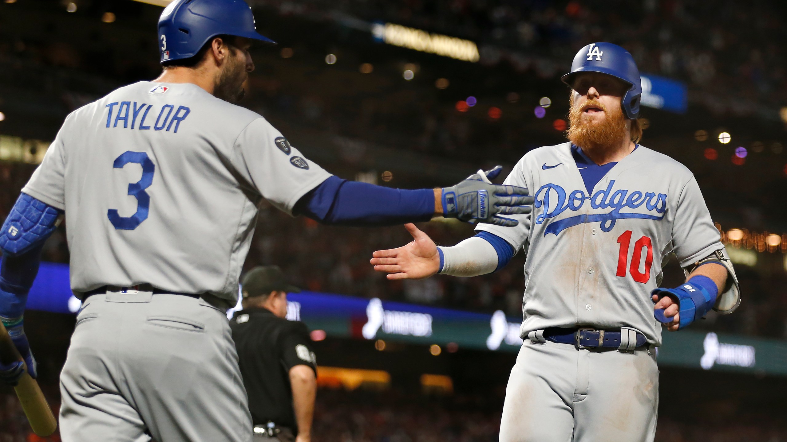 Los Angeles Dodgers' Justin Turner, right, is congratulated by Chris Taylor after scoring against the San Francisco Giants during the ninth inning of Game 5 of a baseball National League Division Series Thursday, Oct. 14, 2021, in San Francisco. (AP Photo/Jed Jacobsohn)