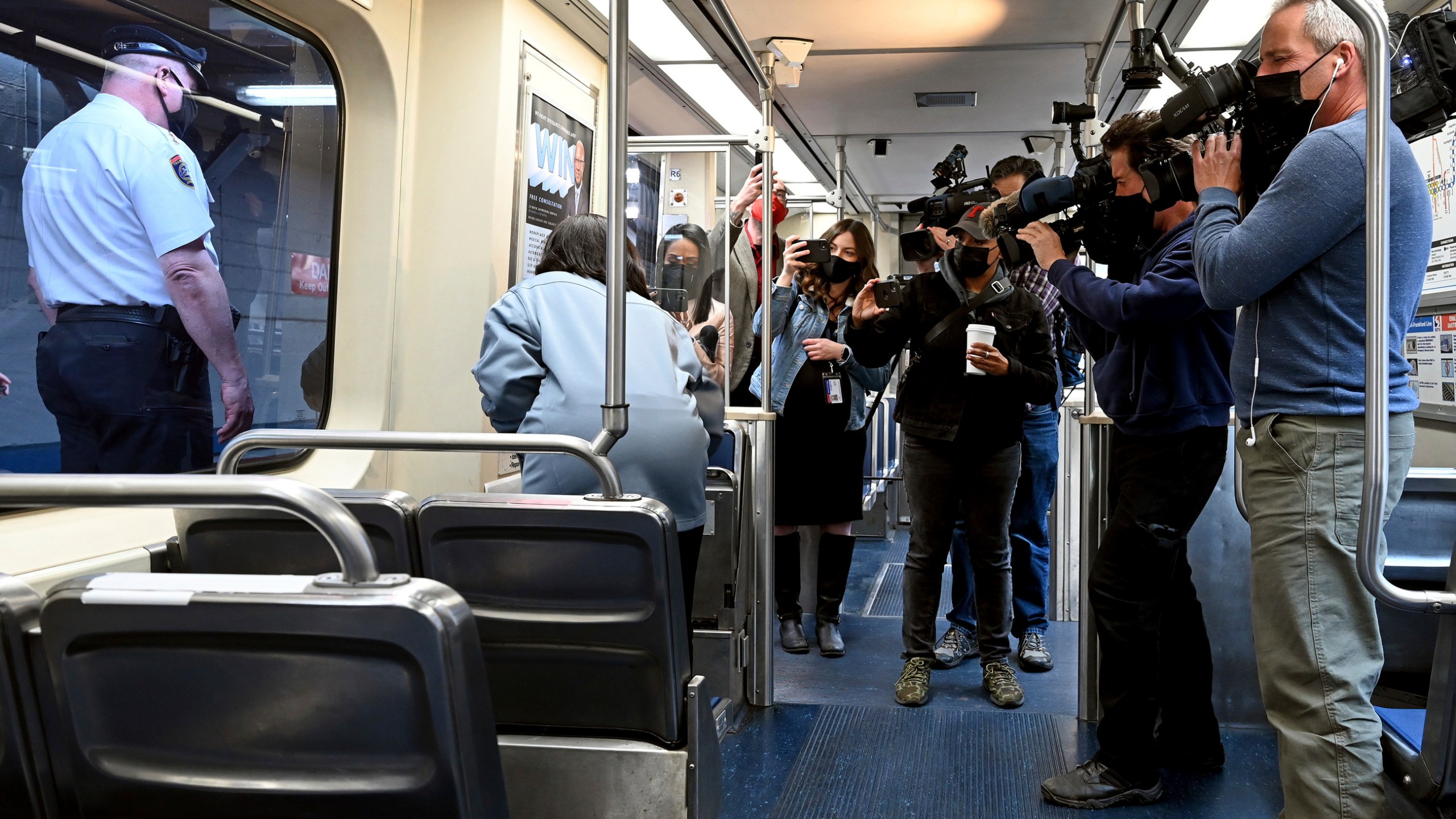 SEPTA Transit Police Chief Thomas Nestel III, seen through window at left, stands by following a news conference on an El platform at the 69th Street Transportation Center, Monday, Oct. 18, 2021, in Philadelphia, following a brutal rape on the El over the weekend. SEPTA subway elevated Chief Officer Chrystalle Hooper, center, demonstrates the emergency call boxes on SEPTA trains and how to properly contact police from their cars. (Tom Gralish/The Philadelphia Inquirer via AP)