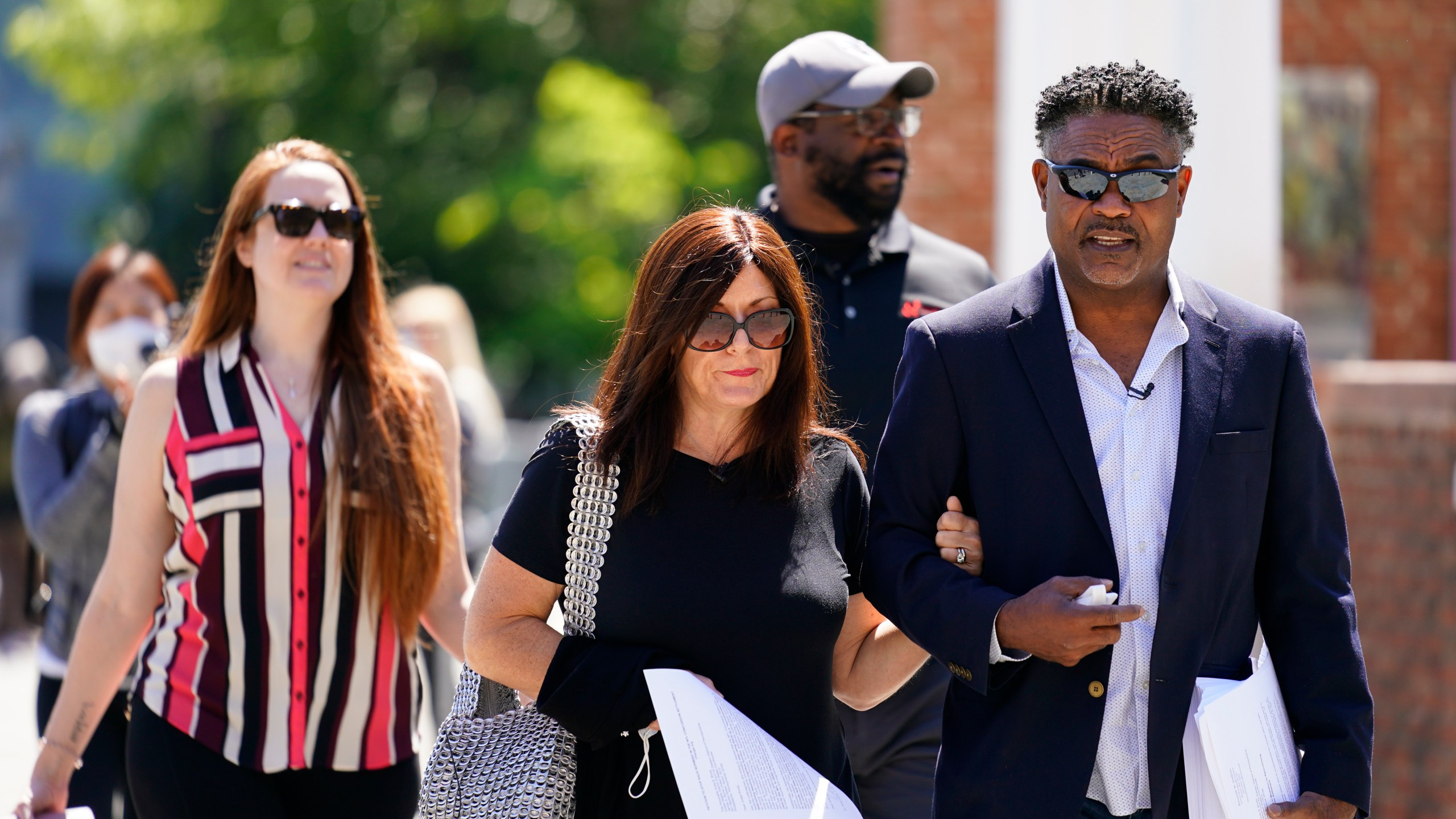 In this May 14, 2021, file photo, former NFL players Ken Jenkins, right, and Clarence Vaughn III, center right, along with their wives, Amy Lewis, center, and Brooke Vaughn, left, carry petitions demanding equal treatment for everyone involved in the settlement of concussion claims against the NFL, to the federal courthouse in Philadelphia on May 14, 2021. (Matt Rourke/Associated Press)