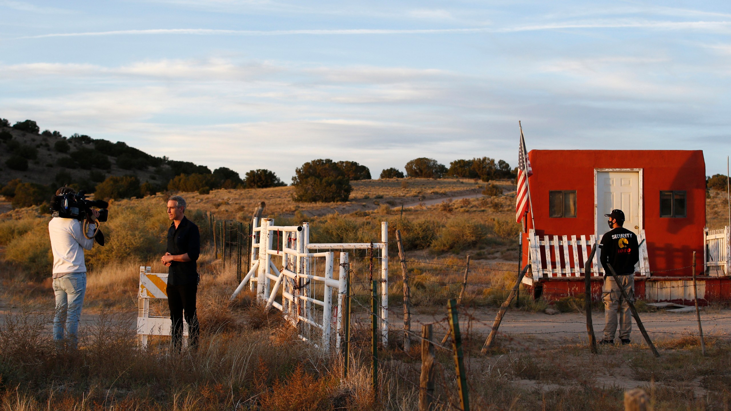 A TV news crew tapes a report at the entrance of the Bonanza Creek Film Ranch in Santa Fe, N.M. Friday, Oct. 22, 2021. Actor Alec Baldwin fired a prop gun on the set of a Western being filmed at the ranch on Thursday, Oct. 21, killing the cinematographer, officials said. The director of the movie was wounded, and authorities were investigating. (AP Photo/Andres Leighton)