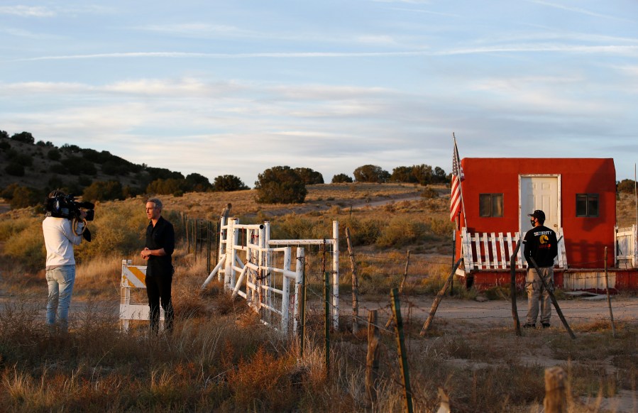 A TV news crew tapes a report at the entrance of the Bonanza Creek Film Ranch in Santa Fe, N.M. Friday, Oct. 22, 2021. Actor Alec Baldwin fired a prop gun on the set of a Western being filmed at the ranch on Thursday, Oct. 21, killing the cinematographer, officials said. The director of the movie was wounded, and authorities were investigating. (AP Photo/Andres Leighton)