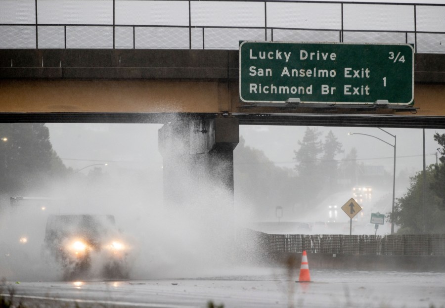 A car drives on Highway 101, which is partially flooded in Corte Madera, Calif., Sunday, Oct. 24, 2021. (AP Photo/Ethan Swope)