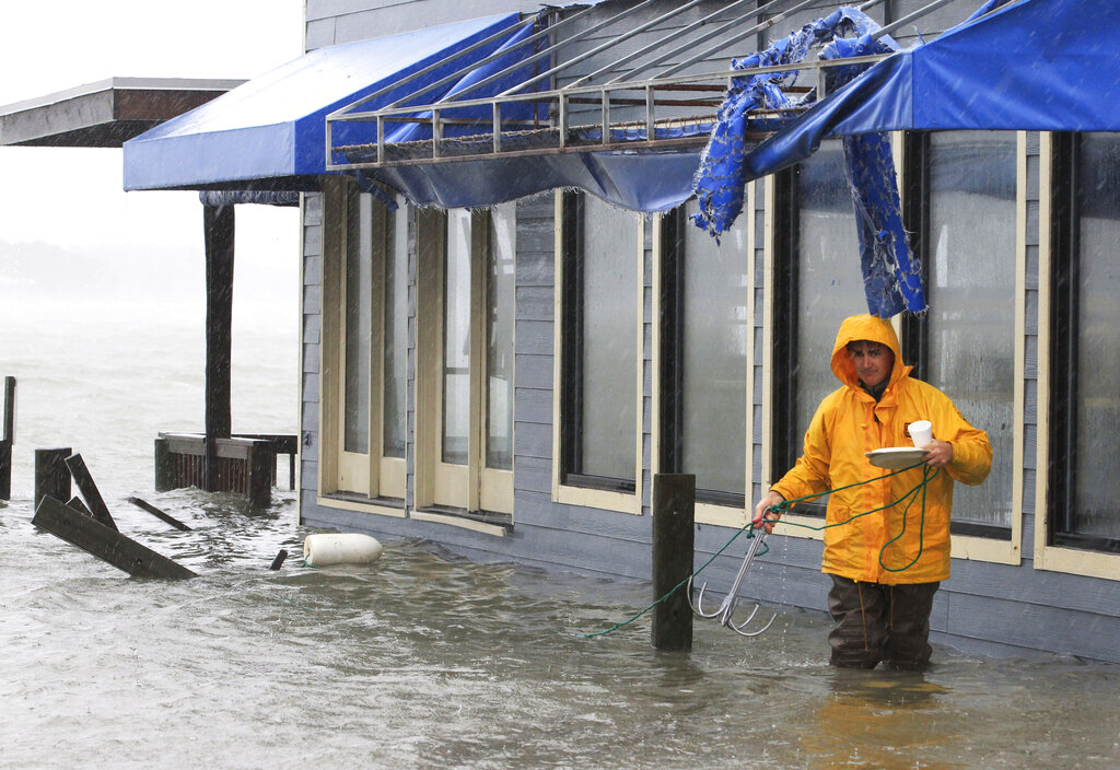 A worker retrieves a grappling hook on the dock next to Bubba's restaurant on the water in Virginia Beach, Va., Monday, Oct. 29, 2012. (AP Photo/Steve Helber)