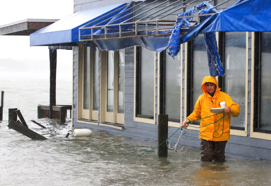 A worker retrieves a grappling hook on the dock next to Bubba's restaurant on the water in Virginia Beach, Va., Monday, Oct. 29, 2012. (AP Photo/Steve Helber)