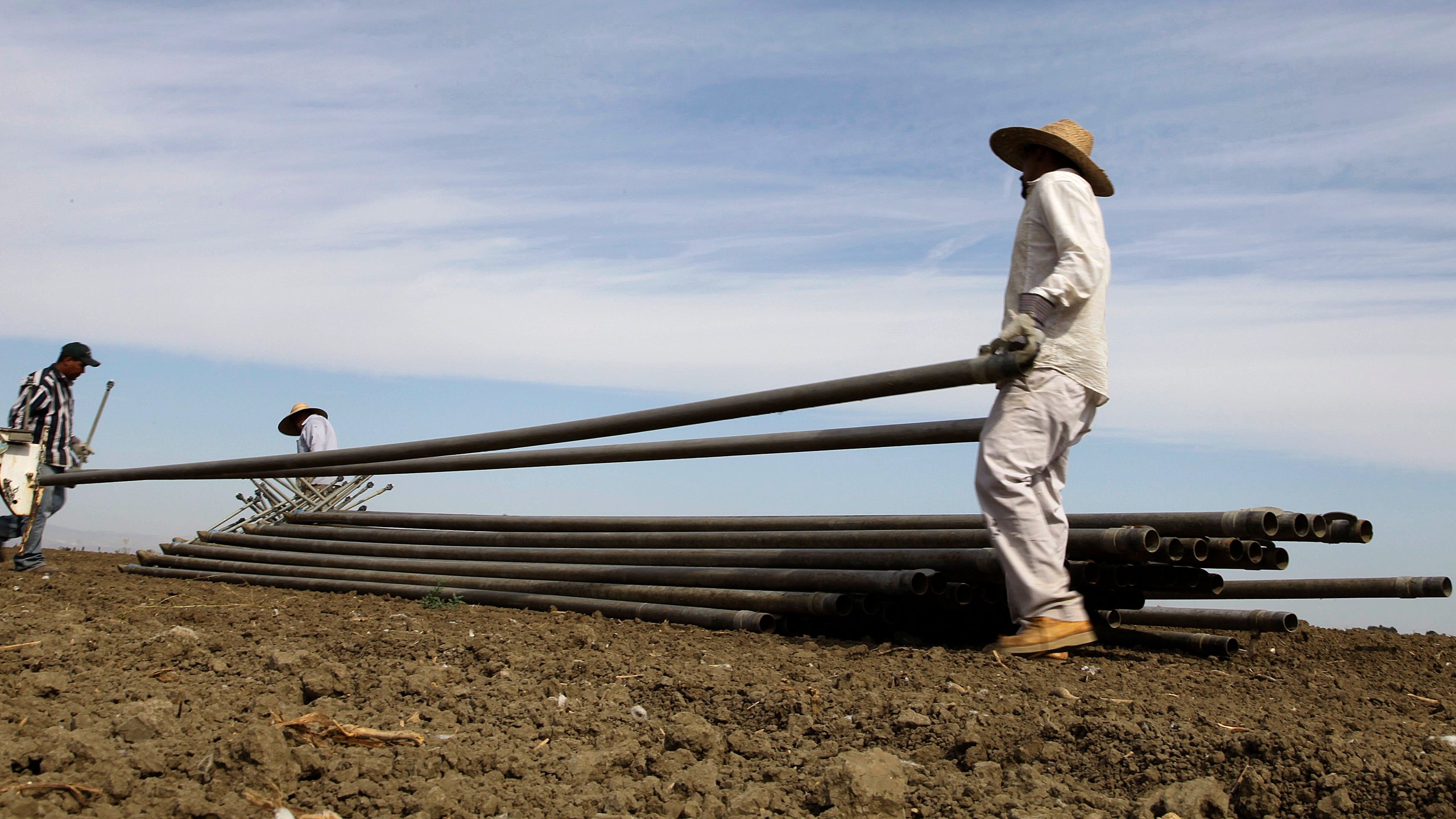 In this June 25, 2013, photo, workers move irrigation pipes from a field in the Westlands Water District near Five Points, Calif. (AP Photo/Gosia Wozniacka, File)