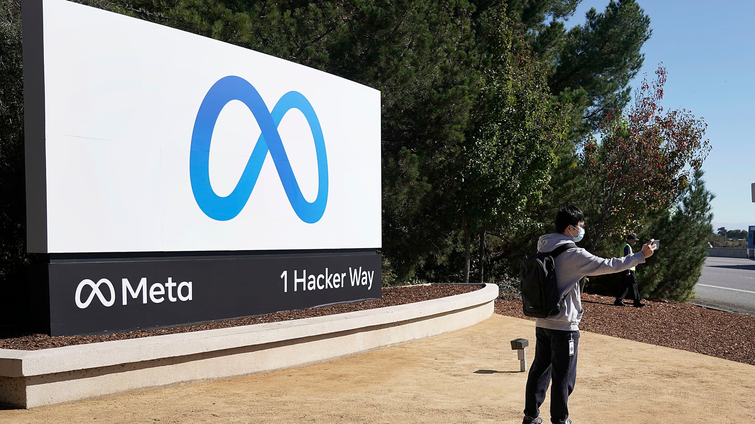 A Facebook employee take a selfie in front the company's new name and logo outside its headquarters in Menlo Park, Calif., Thursday, Oct. 28, 2021, after announcing that it is changing its name to Meta Platforms Inc. (AP Photo/Tony Avelar)