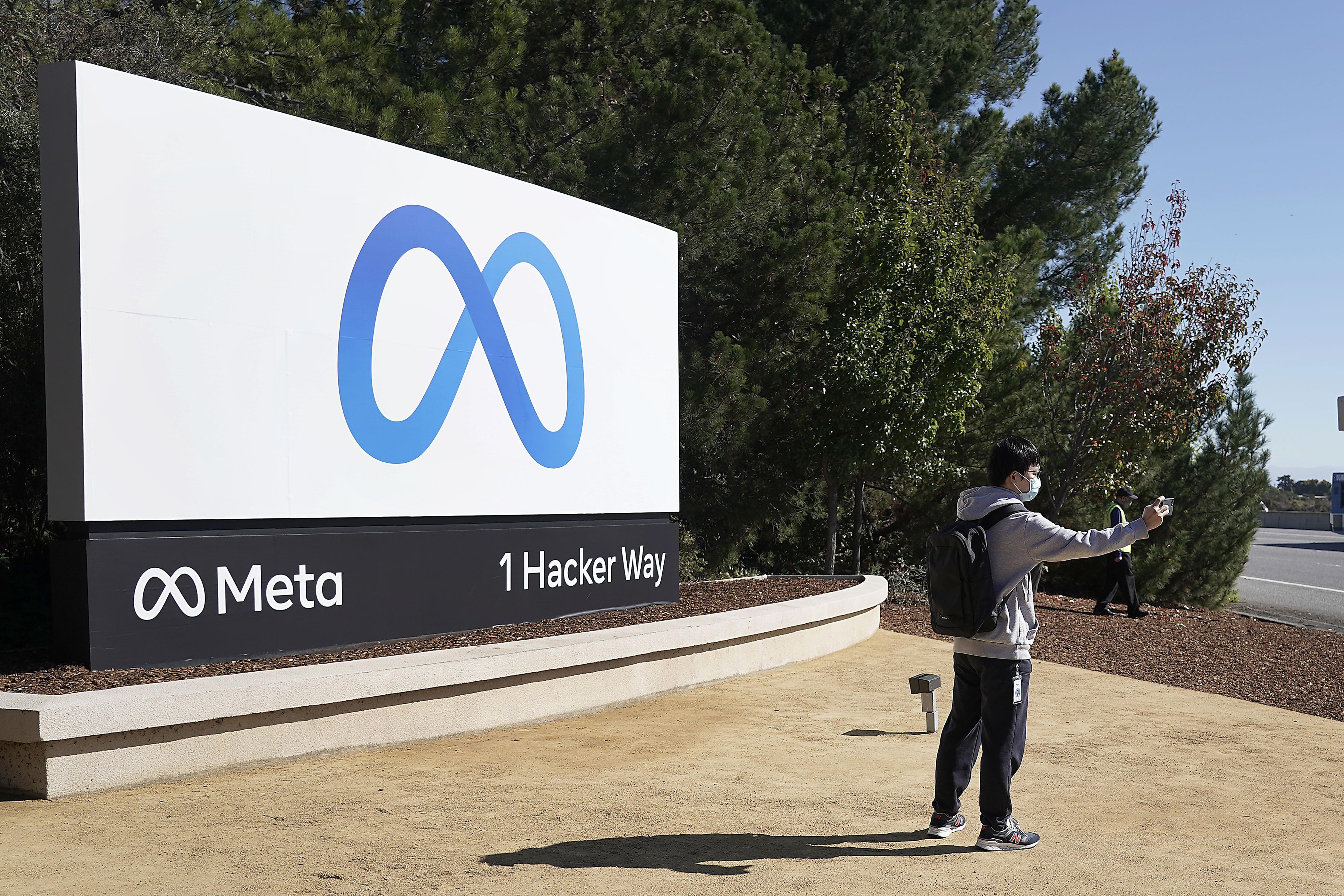 A Facebook employee take a selfie in front the company's new name and logo outside its headquarters in Menlo Park, Calif., Thursday, Oct. 28, 2021, after announcing that it is changing its name to Meta Platforms Inc. (AP Photo/Tony Avelar)