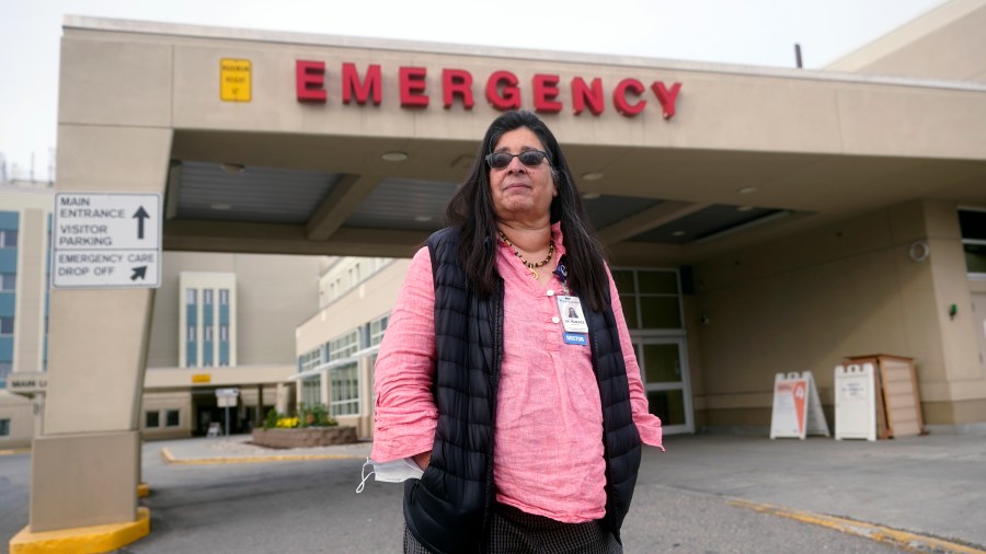 Angelique Ramirez, chief medical officer at Foundation Health Partners in Fairbanks, poses for a photograph in front of the emergency entrance at Fairbanks Memorial Hospital on Tuesday, Sept. 21, 2021, in Fairbanks, Alaska. Fairbanks Memorial Hospital on Friday, Oct. 1, said it activated the Crisis Standards of Care policy because of a critical shortage of bed capacity, staffing and monoclonal antibody treatments, along with the inability to transfer patients to other facilities. (AP Photo/Rick Bowmer)