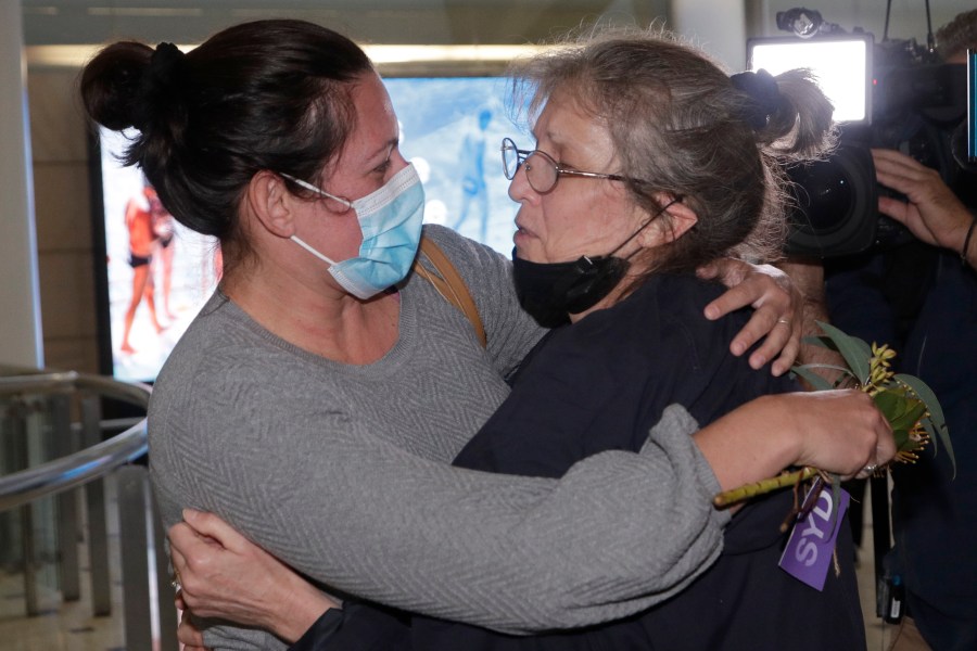 A woman, right, is embraced by. a loved one after arriving on a flight from Los Angeles at Sydney Airport as Australia open its borders for the first time in 19 months in Sydney, Monday, Nov. 1, 2021. International travel will be initially restricted to Sydney's airport because New South Wales has the highest vaccination rate of any state. (AP Photo/Rick Rycroft)