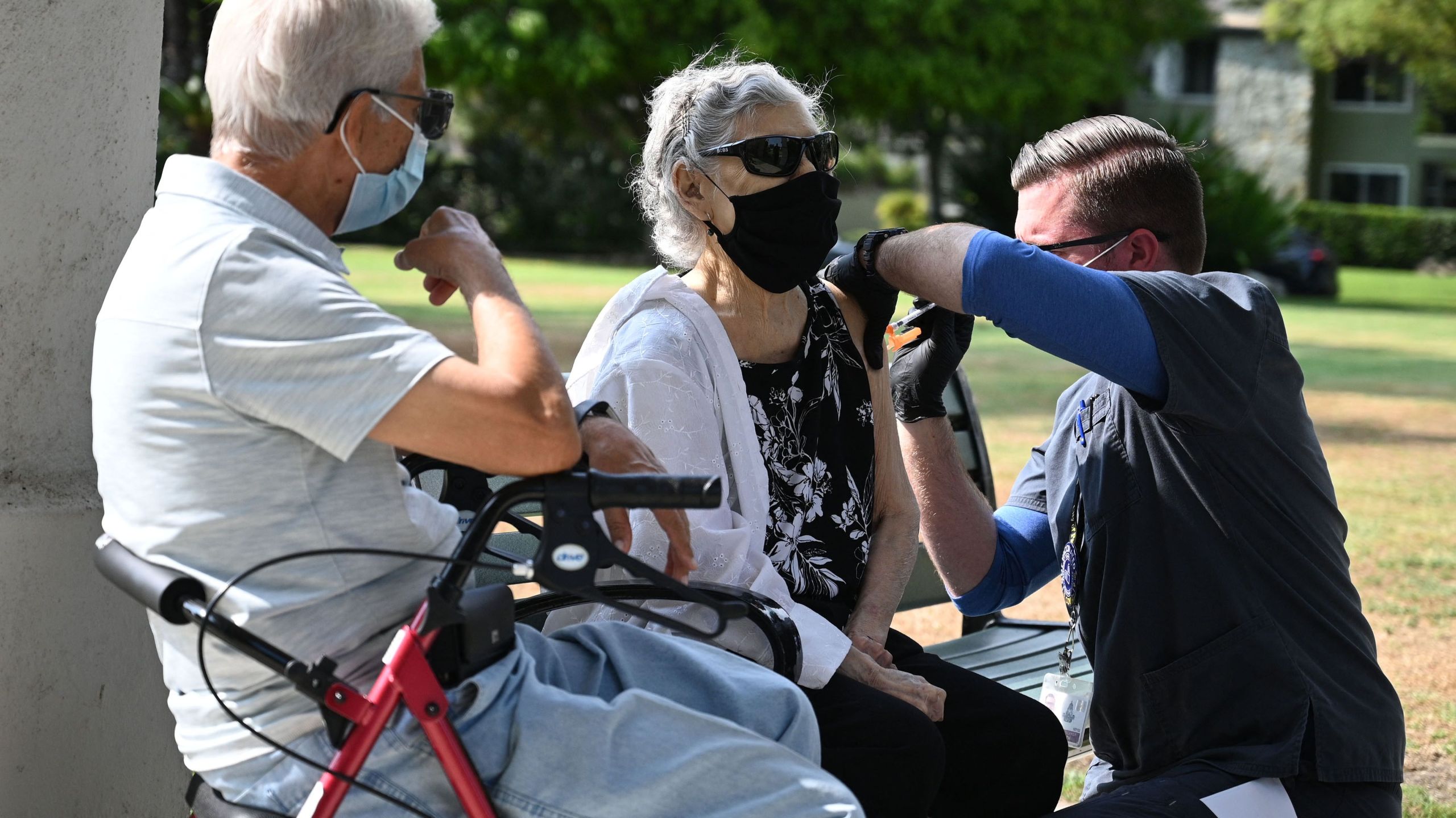 Nurse administers a third booster dose of Pfizer COVID-19 vaccine to Armida Gomez, 81, as her husband Jose Gomez, 80, waits for his turn during a vaccination clinic hosted by Tournament of Roses and the Pasadena Department of Public Health on Aug. 19, 2021 . (ROBYN BECK/AFP via Getty Images)