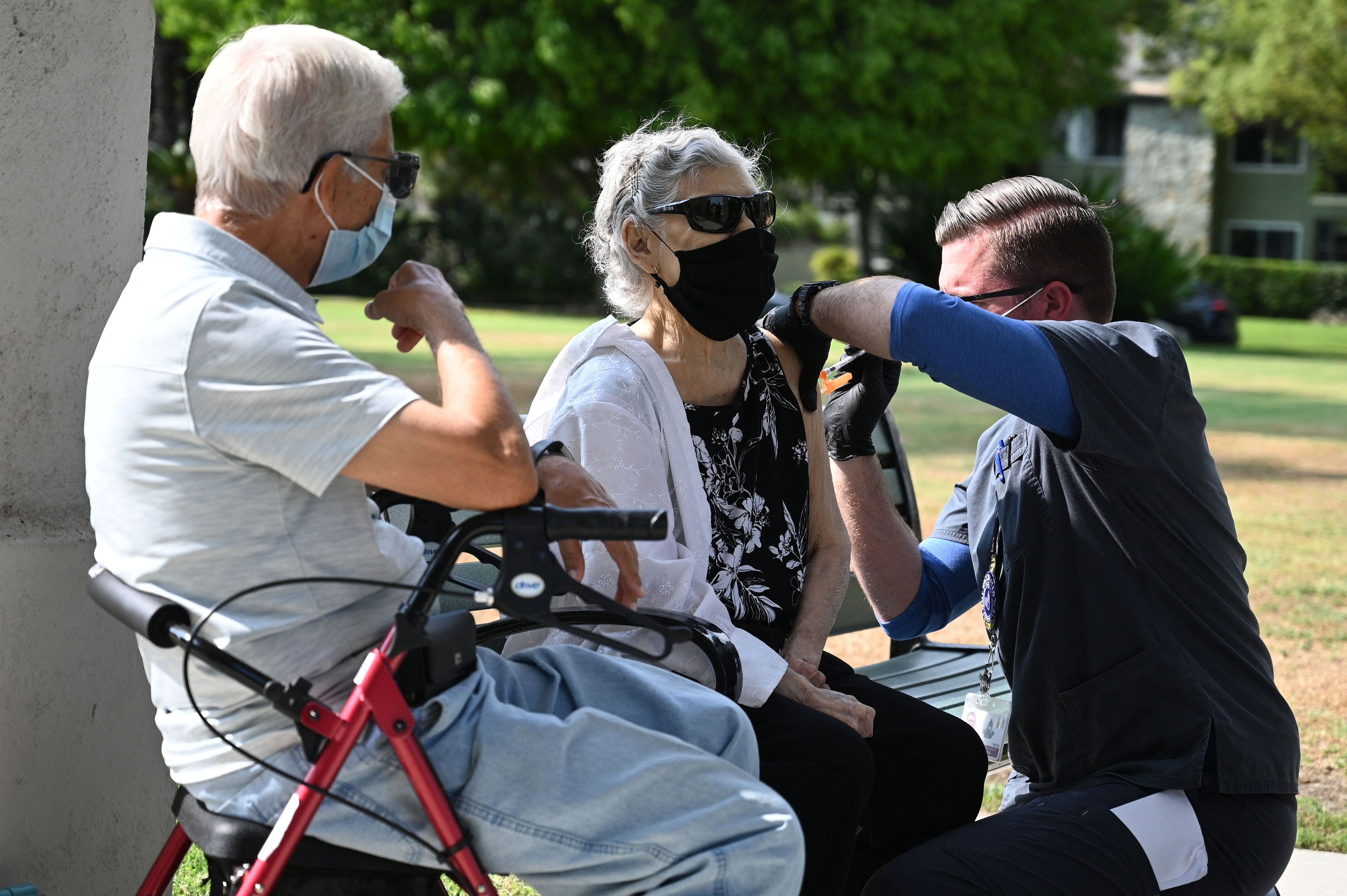 Nurse administers a third booster dose of Pfizer COVID-19 vaccine to Armida Gomez, 81, as her husband Jose Gomez, 80, waits for his turn during a vaccination clinic hosted by Tournament of Roses and the Pasadena Department of Public Health on Aug. 19, 2021 . (ROBYN BECK/AFP via Getty Images)