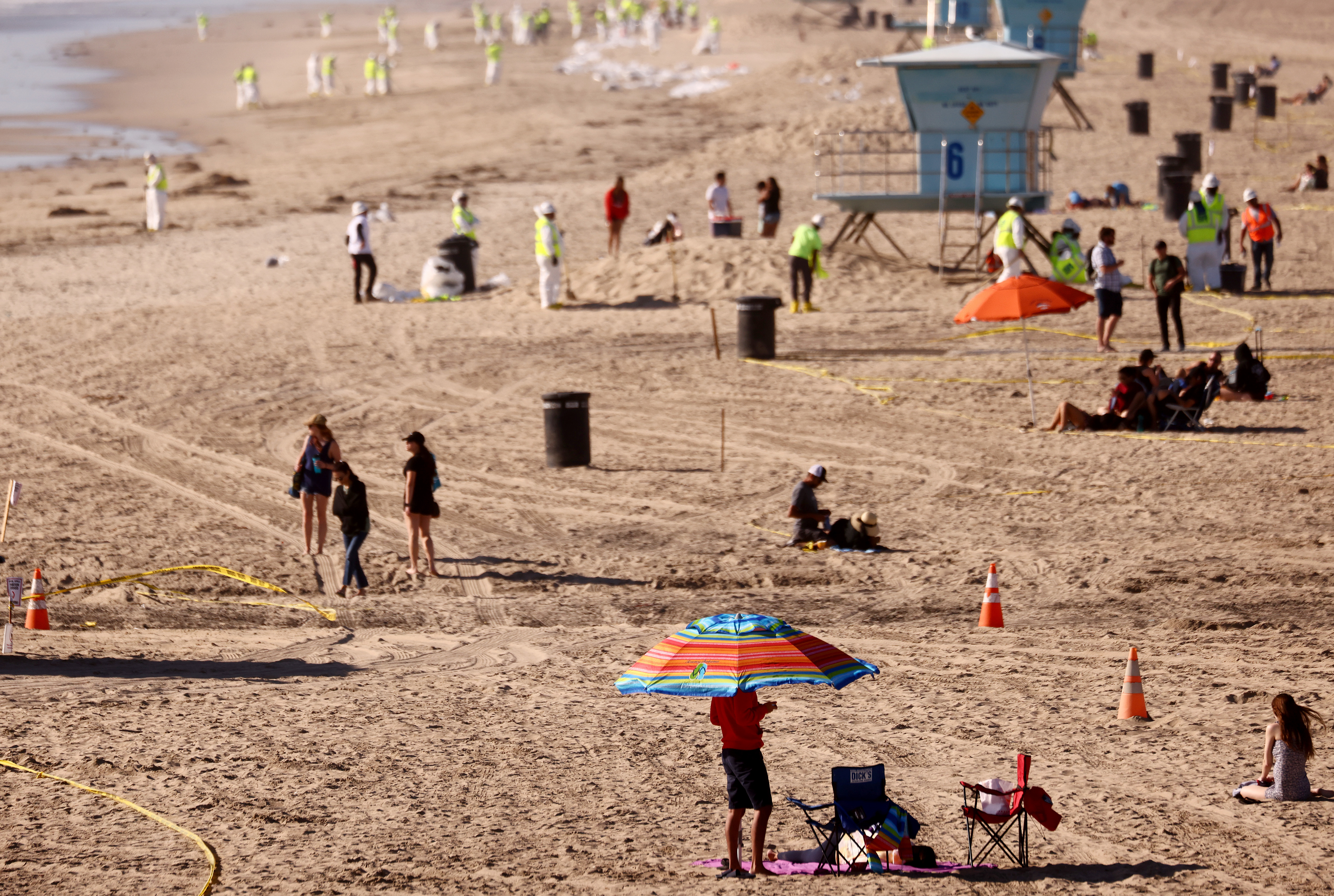 Cleanup workers search for contaminated sand and seaweed on a mostly empty Huntington Beach about one week after an oil spill from an offshore oil platform on Oct. 9, 2021. (Mario Tama / Getty Images)