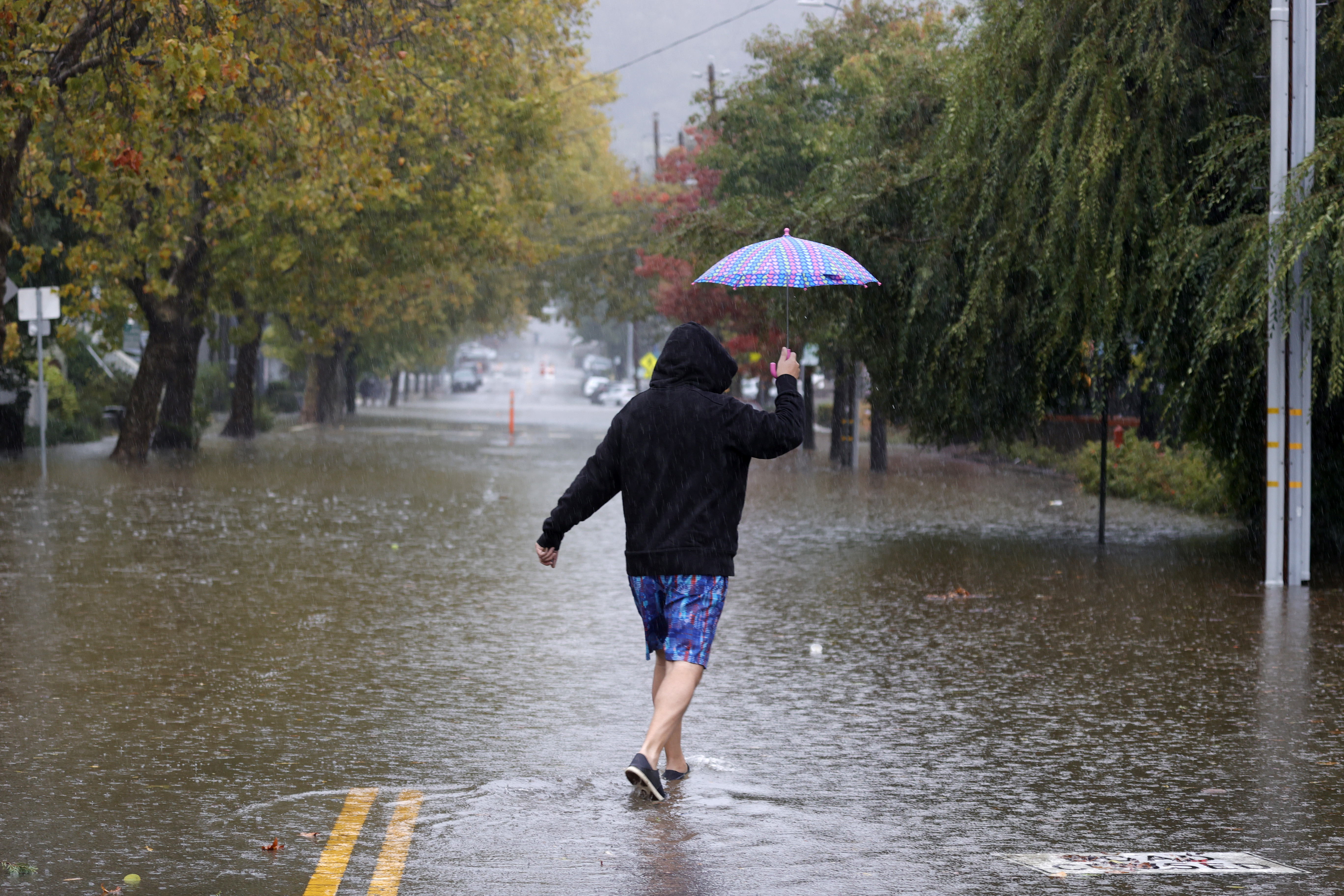 A pedestrian carries an umbrella as he walks on a flooded street on Oct. 24, 2021 in San Rafael. (Justin Sullivan/Getty Images)