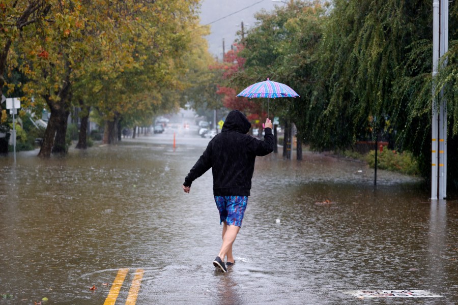 A pedestrian carries an umbrella as he walks on a flooded street on Oct. 24, 2021 in San Rafael. (Justin Sullivan/Getty Images)