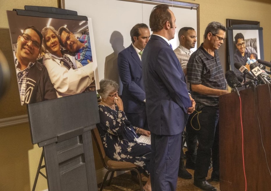 Russell French, right, announces in August 2019 that he and his wife, Paola, who is seated, were suing the city of Los Angeles and former LAPD Officer Salvador Sanchez over Sanchez’s fatal shooting of their son, Kenneth French, inside a Costco in Corona. The photo at left shows Kenneth French in 2014 with his parents, who were also shot by Sanchez.(Mel Melcon/Los Angeles Times)