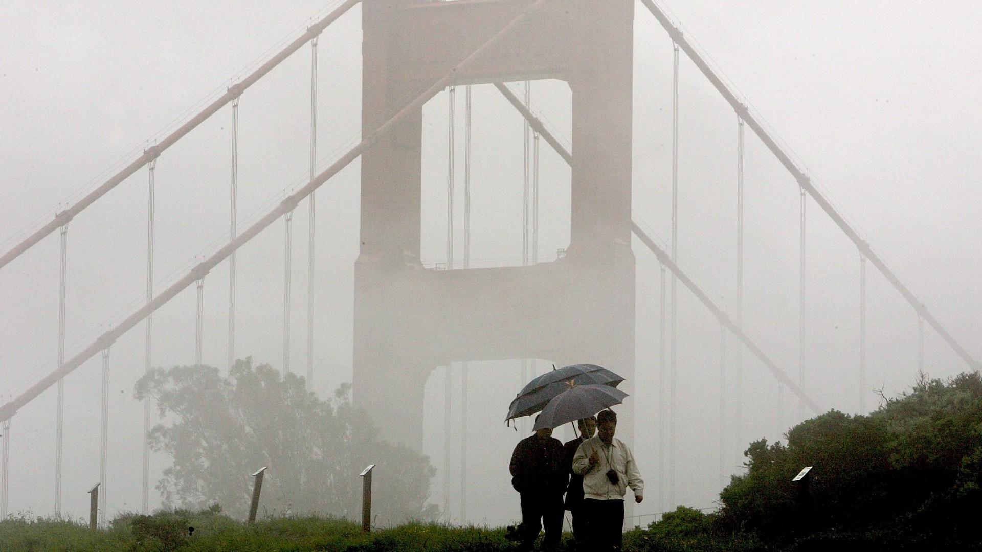 A group of men walk through the rain near the north tower of the Golden Gate Bridge April 12, 2006 in Sausalito. (Justin Sullivan/Getty Images)