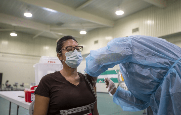 A nurse gives a COVID-19 vaccine shot to special education assistant Roxanne Juarez at Eagle Rock Junior/Senior High School in August. School officials on Monday pushed back an Oct. 15 for full vaccination.(Allen J. Schaben / Los Angeles Times)