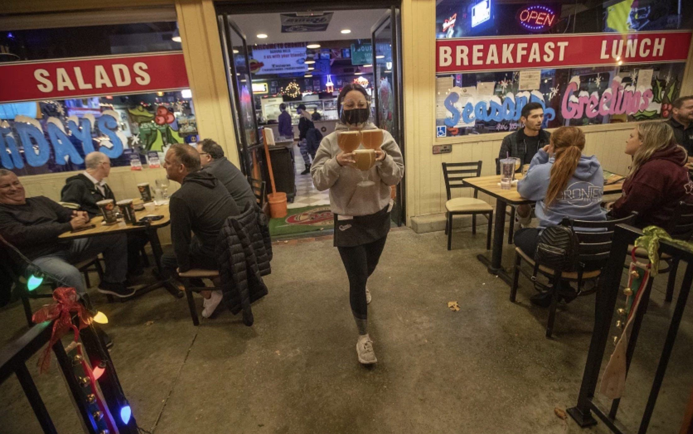 Waitress Shannon Kaufman makes her way with a handful of beers in December while serving customers in the outdoor dining area at Cronies Sports Grill in Agoura Hills. (Mel Melcon / Los Angeles Times)