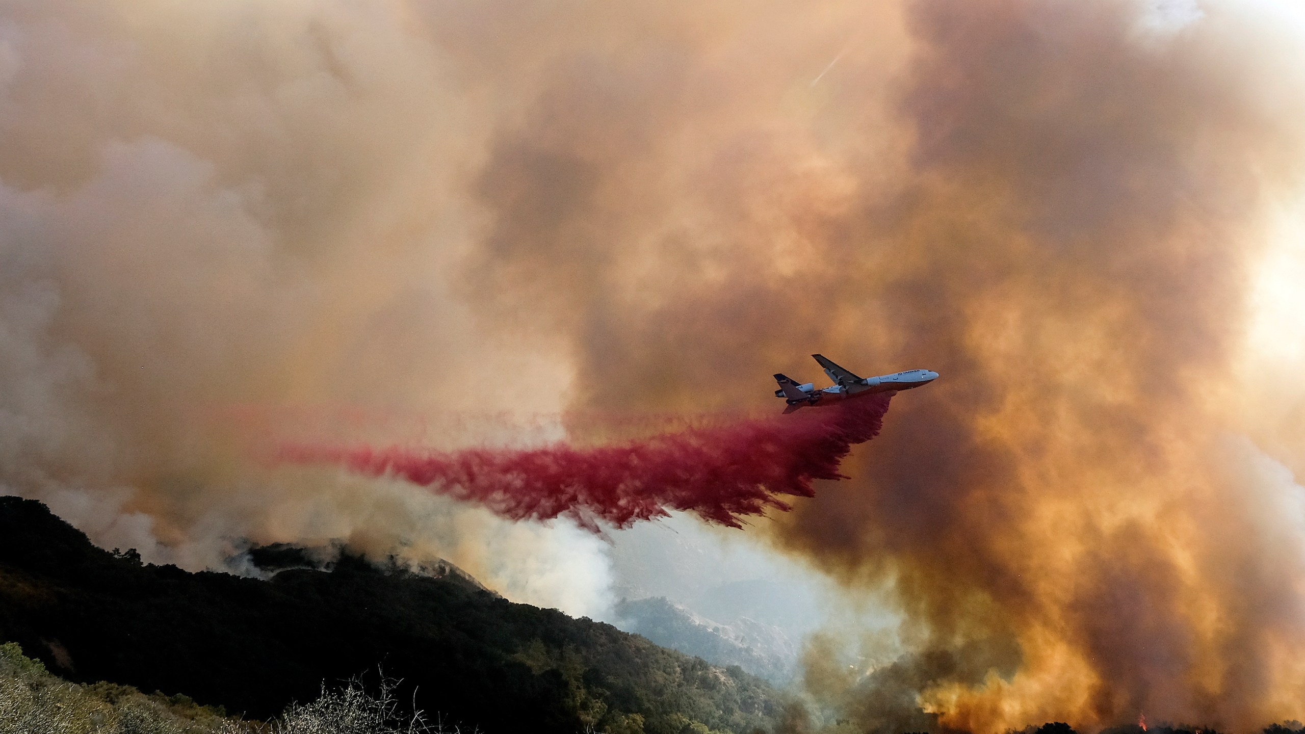 In this Oct. 13, 2021 photo, an air tanker drops retardant on a wildfire in Goleta, Calif. Firefighters persisted in making progress Saturday, Oct. 17, against a wildfire burning for a sixth day in Southern California coastal mountains. The Alisal Fire in the Santa Ynez Mountains west of Santa Barbara grew only slightly since Friday to nearly 27 square miles (69 square kilometers). It was 50% contained. (AP Photo/Ringo H.W. Chiu)