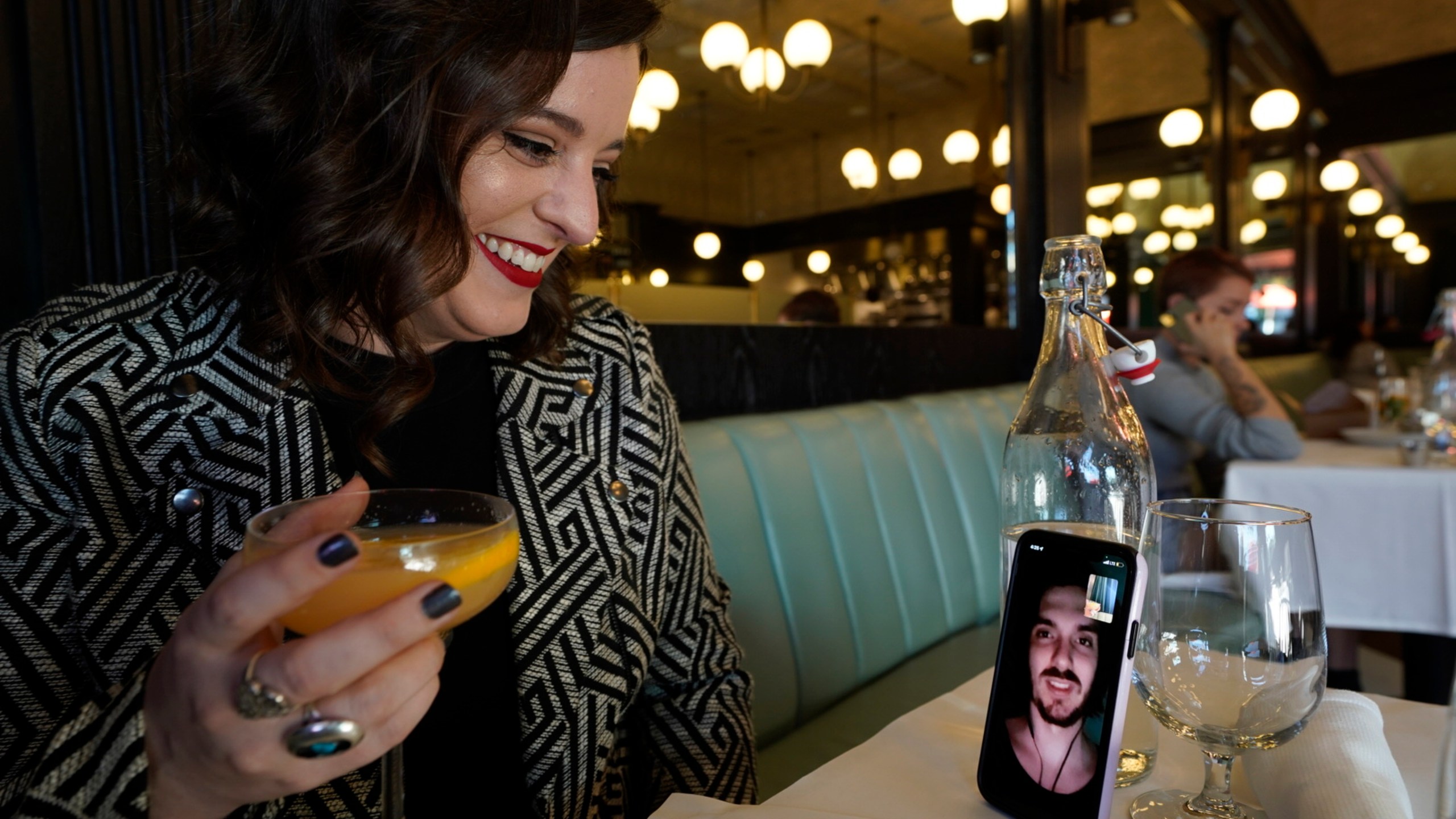 Erin Tridle holds a video chat with her boyfriend Jordan Commarrieu living in Paris from their favorite French restaurant "Petit Trois" in Los Angeles on Friday, Nov. 5, 2021. (AP Photo/Damian Dovarganes)