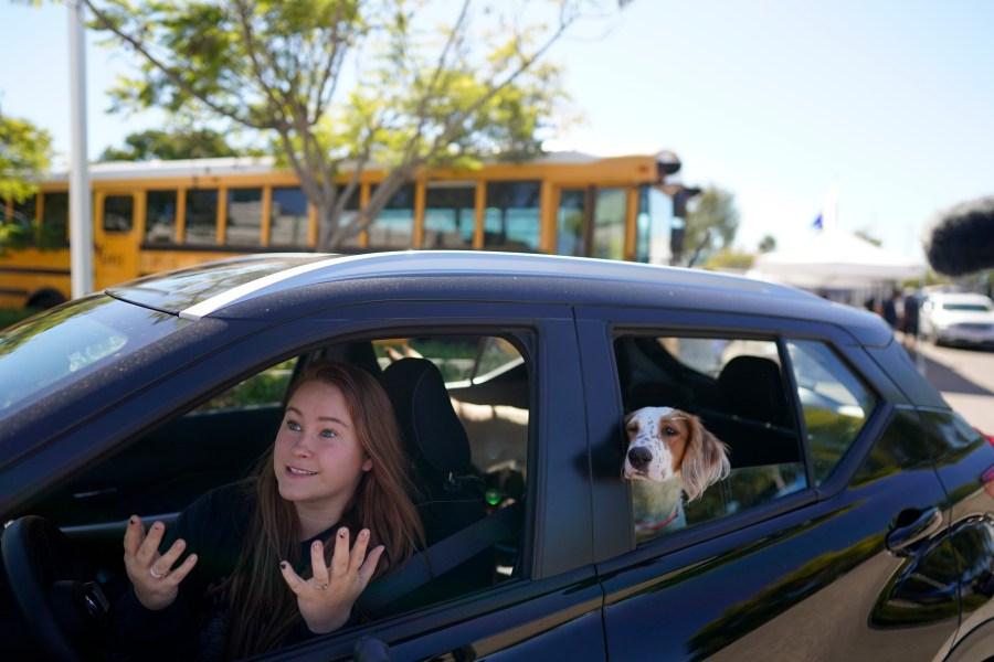 Brooklyn Pittman talks as she sits in her car with her dogs after receiving food from an Armed Services YMCA food distribution, Oct. 28, 2021, in San Diego. (AP Photo/Gregory Bull)