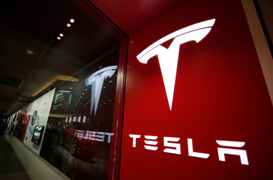 This Feb. 9, 2019, file photo shows a sign bearing the company logo outside a Tesla store in Cherry Creek Mall in Denver. (AP Photo/David Zalubowski, File)