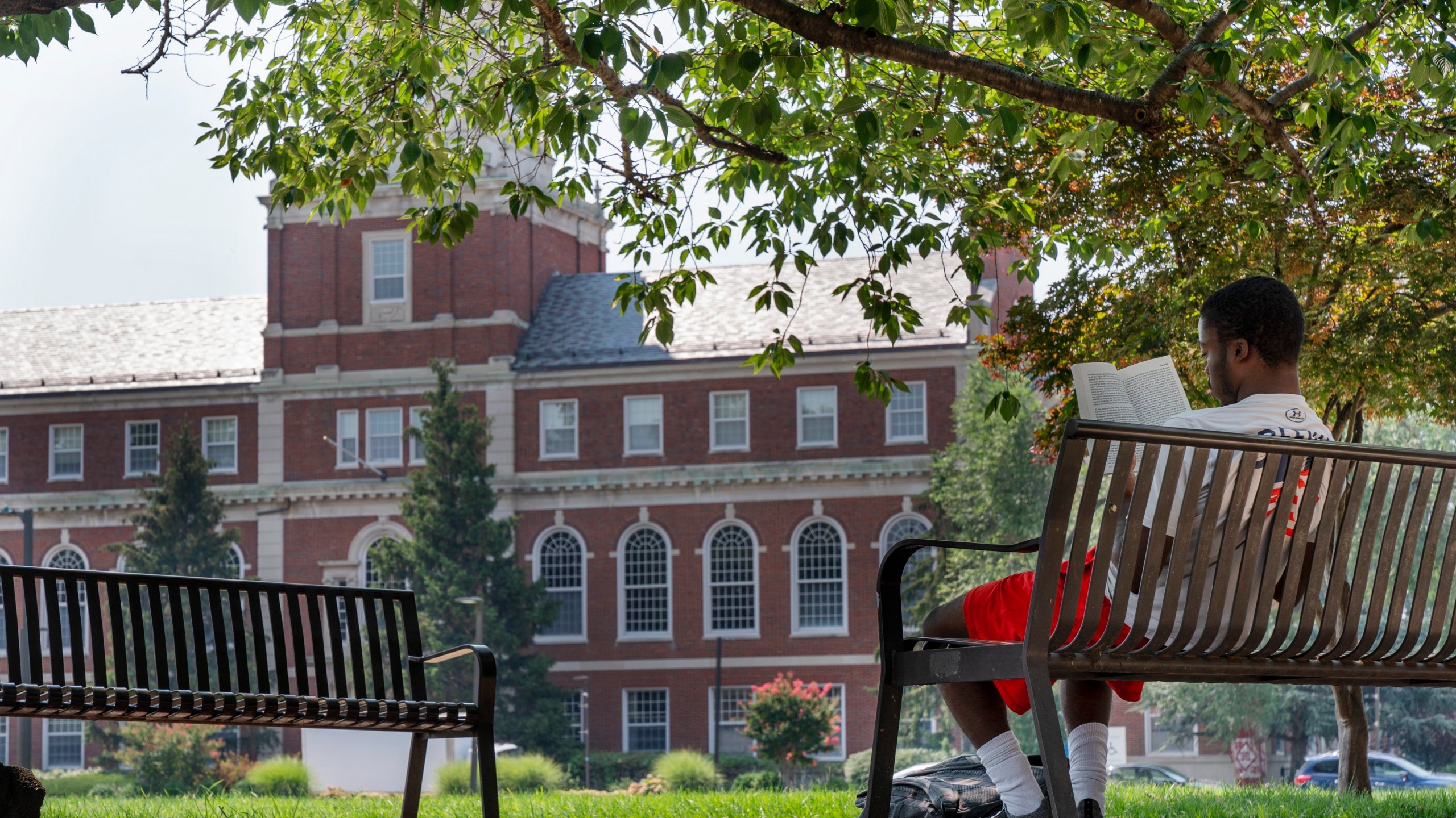 With the Founders Library in the background, a young man reads on Howard University campus July 6, 2021, in Washington. Nationwide, American colleges and universities saw a 4% annual increase in international students this fall, according to survey results released Monday, Nov. 15, by the Institute of International Education. But that follows a decrease of 15% last year, the steepest decline since the institute began publishing data in 1948. (AP Photo/Jacquelyn Martin, File)