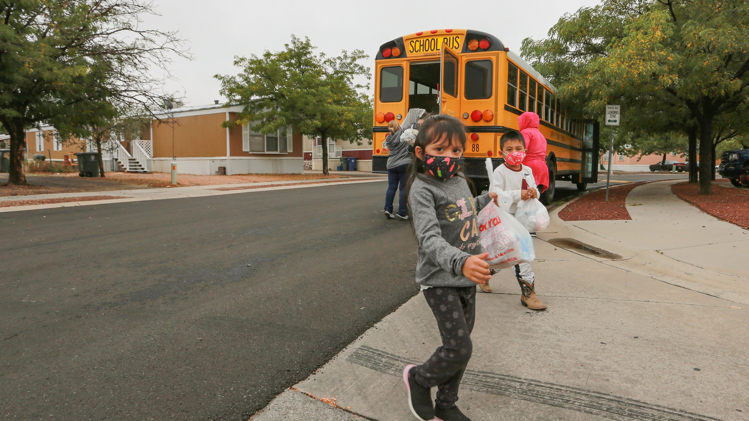 Kindergarteners who are learning remotely during the coronavirus pandemic pick up meals at a bus stop near their home in Santa Fe, N.M., on Sept. 9, 2020. The Santa Fe school district decided last week to close its doors on Nov. 23, 2021, and pivot to remote learning in a bid to reduce virus outbreaks ahead of the Thanksgiving holiday. (Cedar Attanasio/Associated Press)