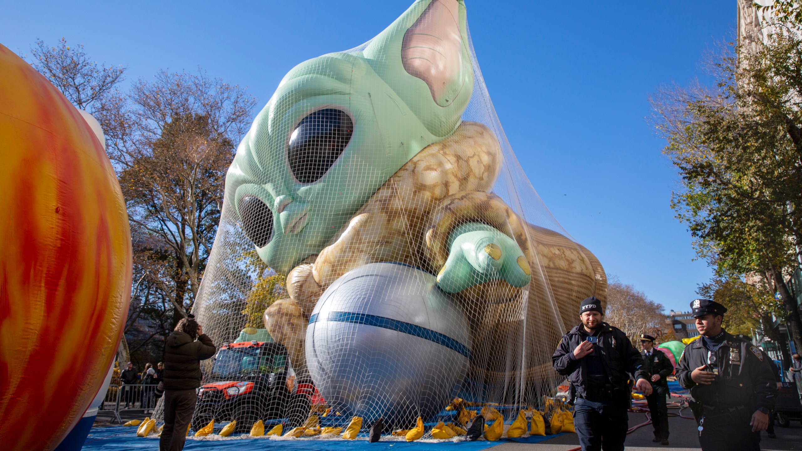 Police walk by an inflated helium balloon of Grogu, also known as Baby Yoda, from the Star Wars show The Mandalorian, Wednesday, Nov. 24, 2021, in New York, as the balloon is readied for the Macy's Thanksgiving Day Parade on Thursday. (AP Photo/Ted Shaffrey)