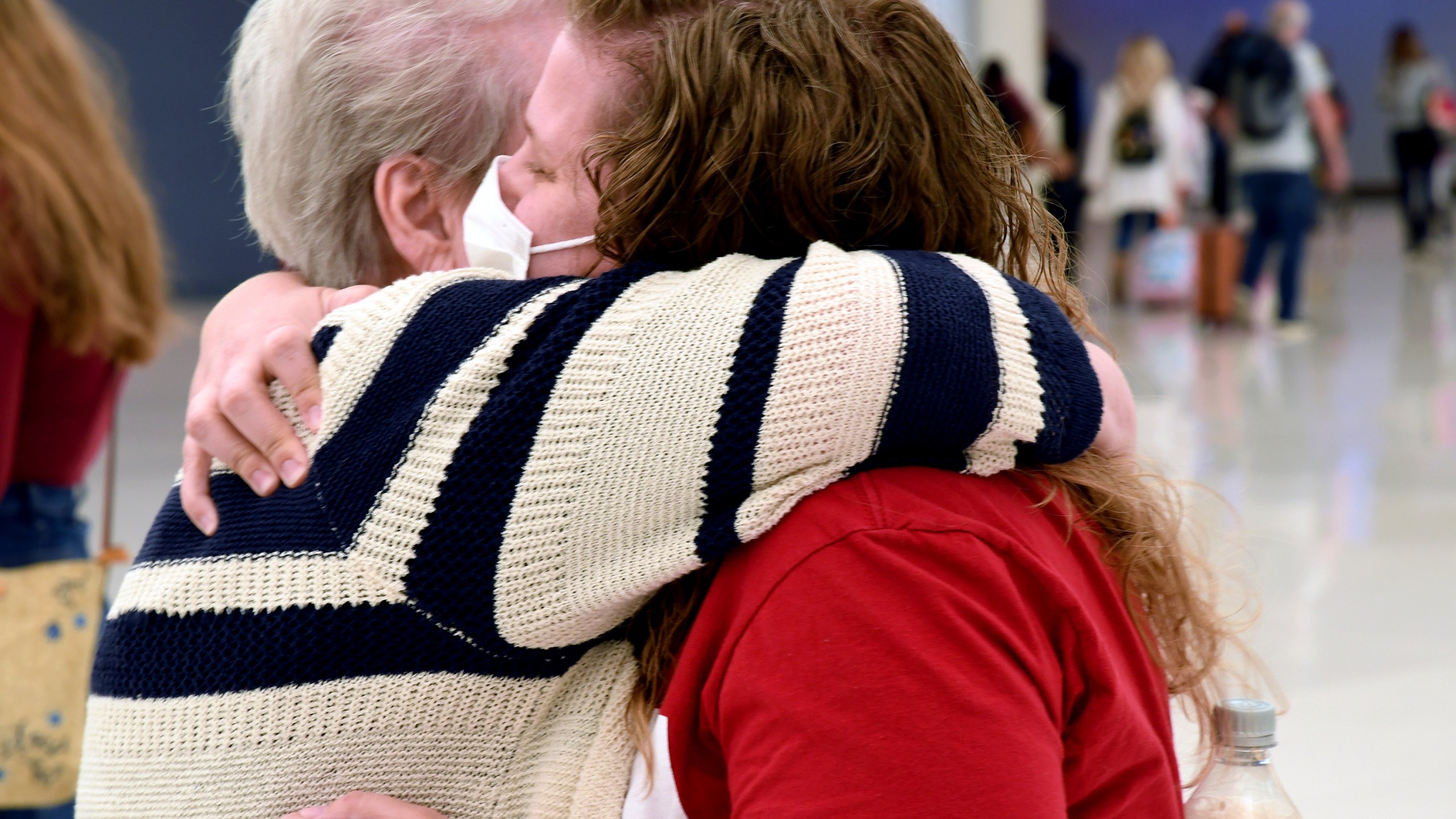 Jocelyn Ragusin hugs her mother, who arrived at Denver International Airport from Rapid City, South Dakota, on Tuesday, Nov. 23, 2021. Ragusin said about seven or eight family members would be gathering for the holiday and that the group had not discussed each other's vaccination status beforehand. Ragusin's husband contracted COVID-19 and spent four days in the intensive care unit in October 2020, but the family is willing to accept a certain level of risk to have a sense of community back. (AP Photo/Thomas Peipert)