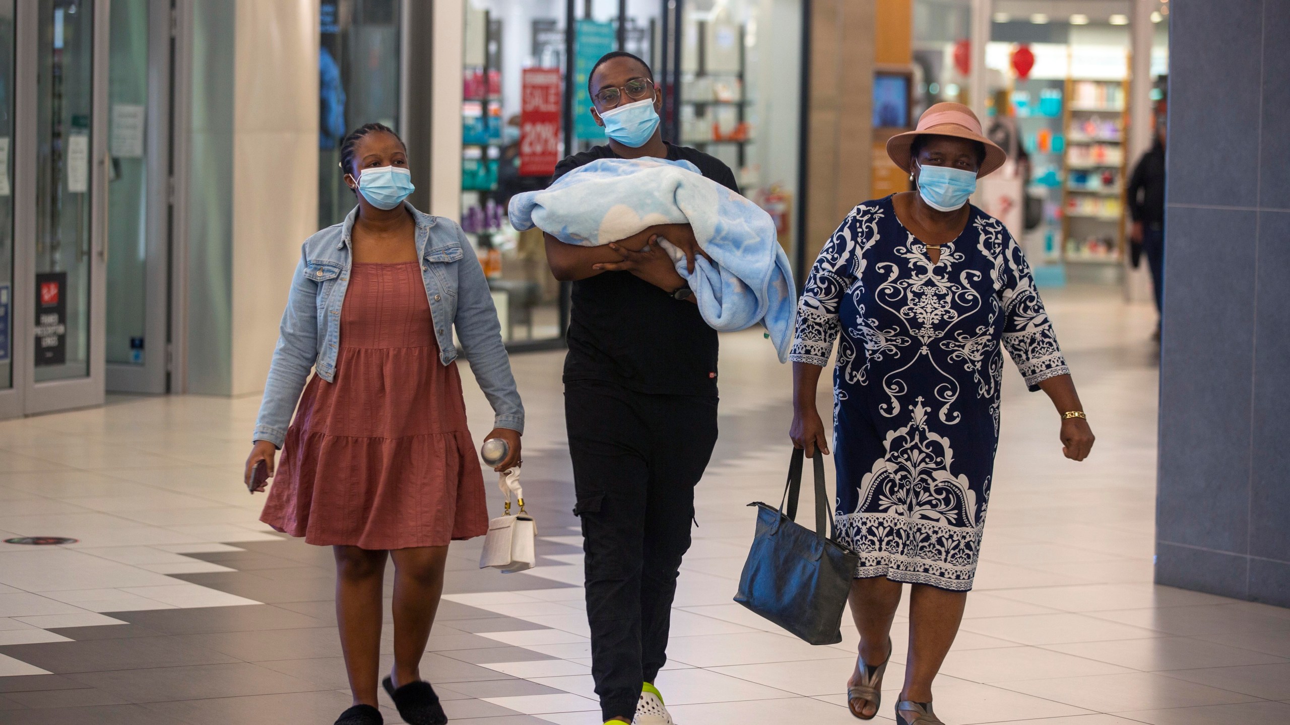 People with masks walk at a shopping mall in Johannesburg, South Africa on Nov. 26, 2021. (AP Photo/Denis Farrell)