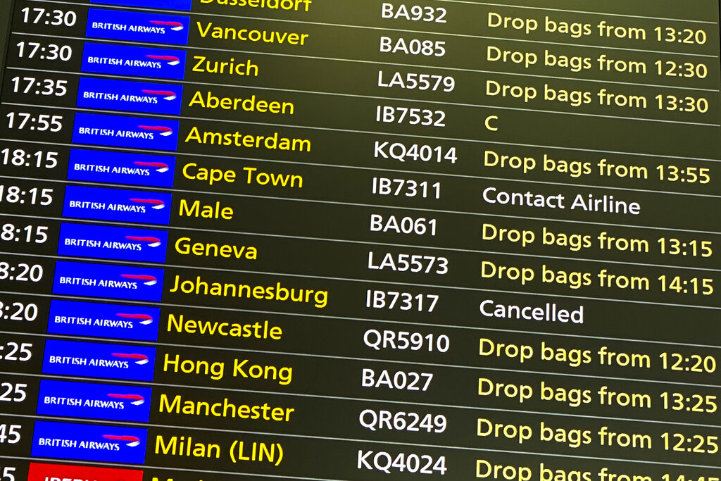 A departures screen displays a cancelled flight to Johannesburg and a message to contact the airline for a scheduled flight to Capetown, at London's Heathrow Airport, Friday, Nov. 26, 2021. (AP Photo/Alberto Pezzali)