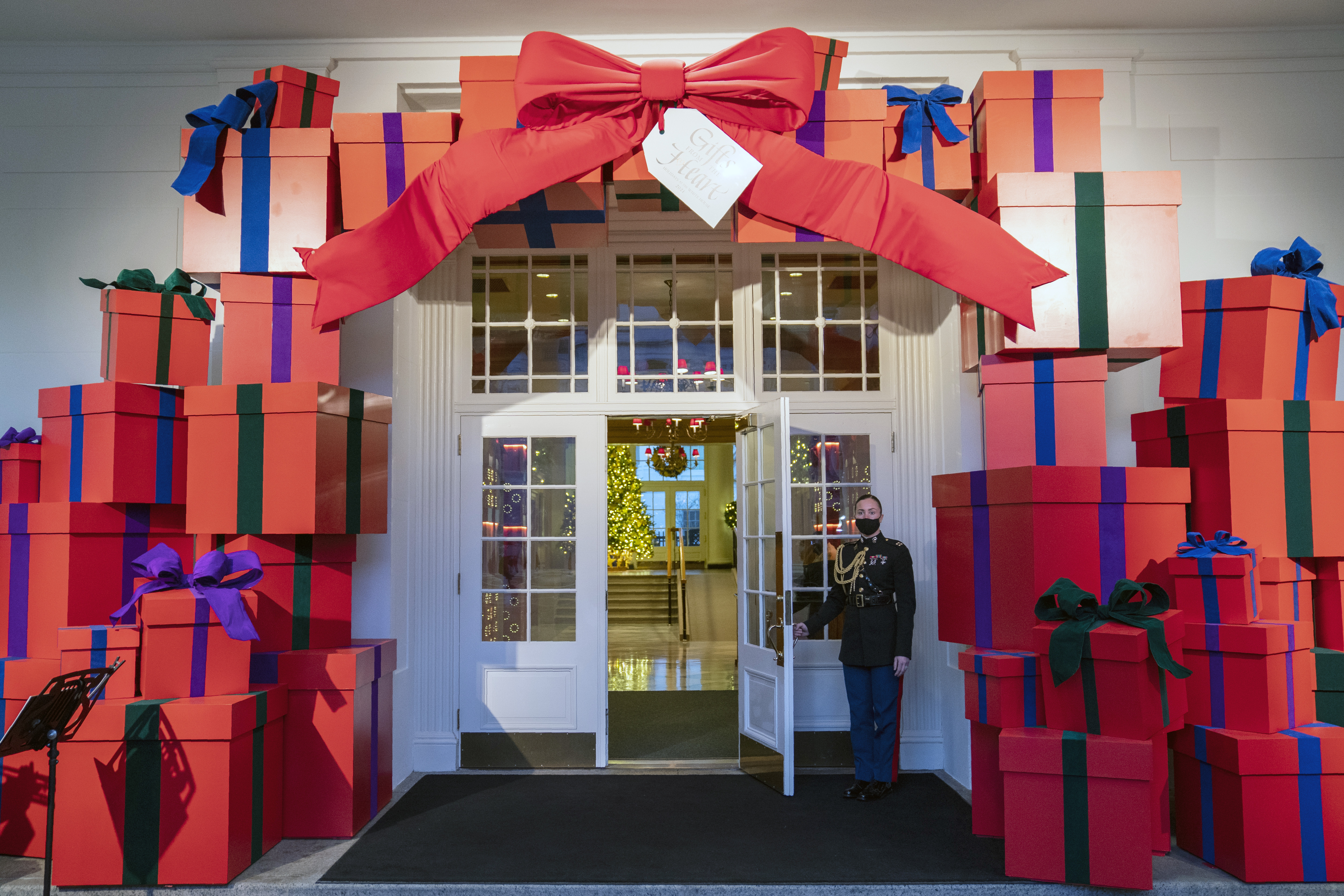 A Marine White House Military social aide holds the door to the East Wing entrance of the White House during a press preview of the White House holiday decorations, Monday, Nov. 29, 2021, in Washington. (AP Photo/Evan Vucci)