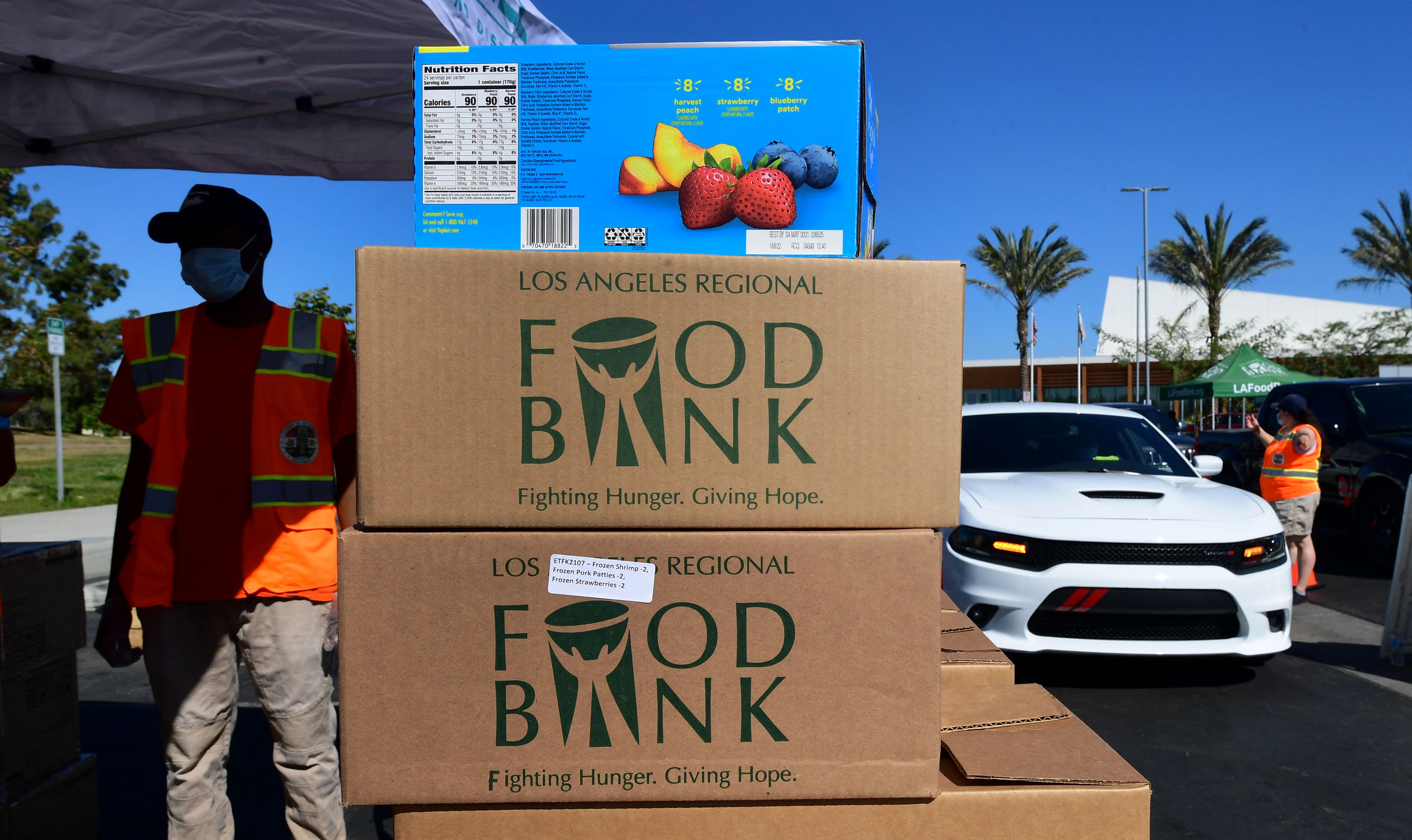 Los Angeles County Regional Food Bank workers help with food distribution to some 2,000 vehicles in Willowbrook, California on April 29, 2021 in an ongoing effort to help people affected by the coronavirus pandemic. (FREDERIC J. BROWN/AFP via Getty Images)