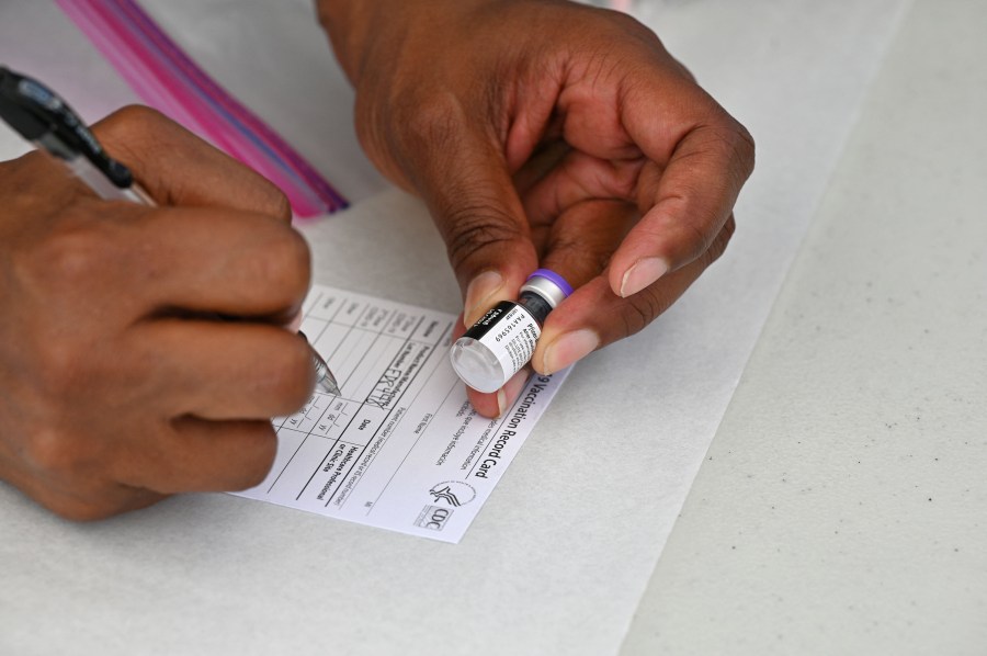 A healthcare worker fills out a Covid-19 vaccination card at a community healthcare event in a predominately Latino neighborhood in Los Angeles, Aug. 11, 2021. (ROBYN BECK/AFP via Getty Images)