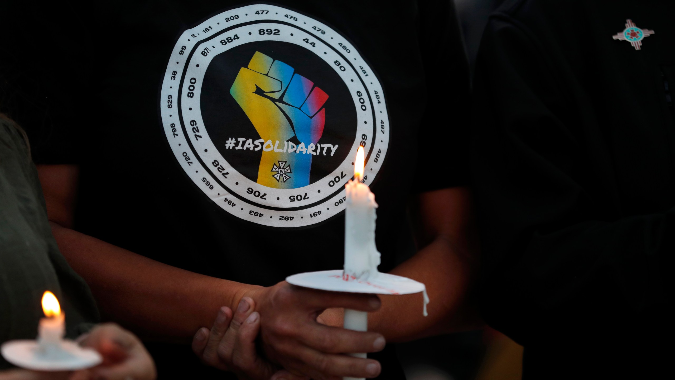 Movie industry worker Hailey Josselyn, wearing a t-shirt of the International Alliance of Theatrical Stage Employees (IATSA), holds a candle during a vigil to honor cinematographer Halyna Hutchins in Albuquerque, N.M., on Oct. 23, 2021. Hutchins was fatally shot on Thursday, Oct. 21, after an assistant director unwittingly handed actor Alec Baldwin a loaded weapon and told him it was safe to use on the set of a Western filmed in Santa Fe, N.M. Members of the IATSA,will vote on a proposed three-year union contract with Hollywood producers. (AP Photo/Andres Leighton, File)