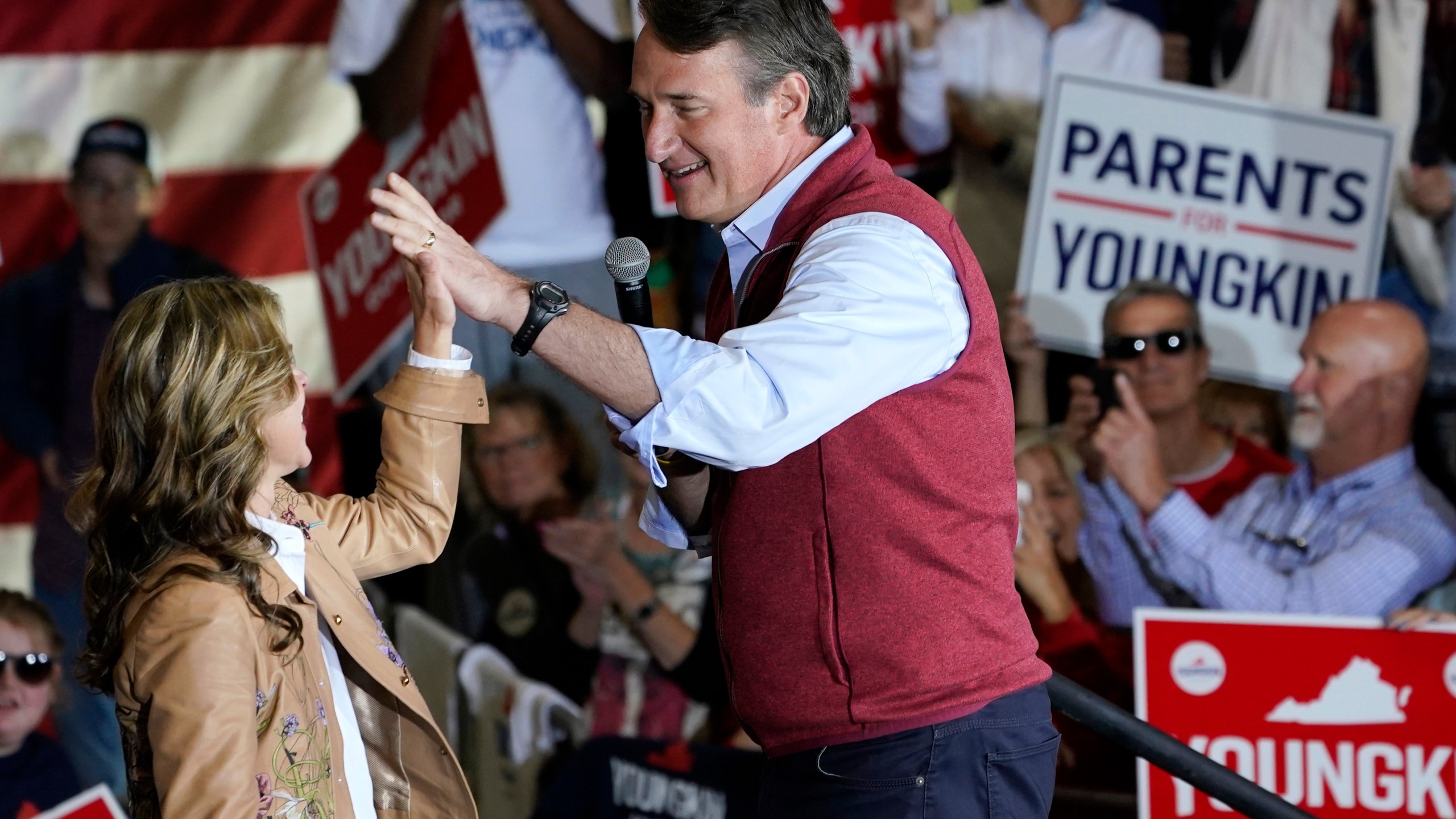 Republican gubernatorial candidate Glenn Youngkin, right, gives his wife Suzanne, a high five during a rally in Chesterfield, Va., Monday, Nov. 1, 2021. Youngkin will face Democrat former Gov. Terry McAuliffe in the November election. (AP Photo/Steve Helber)