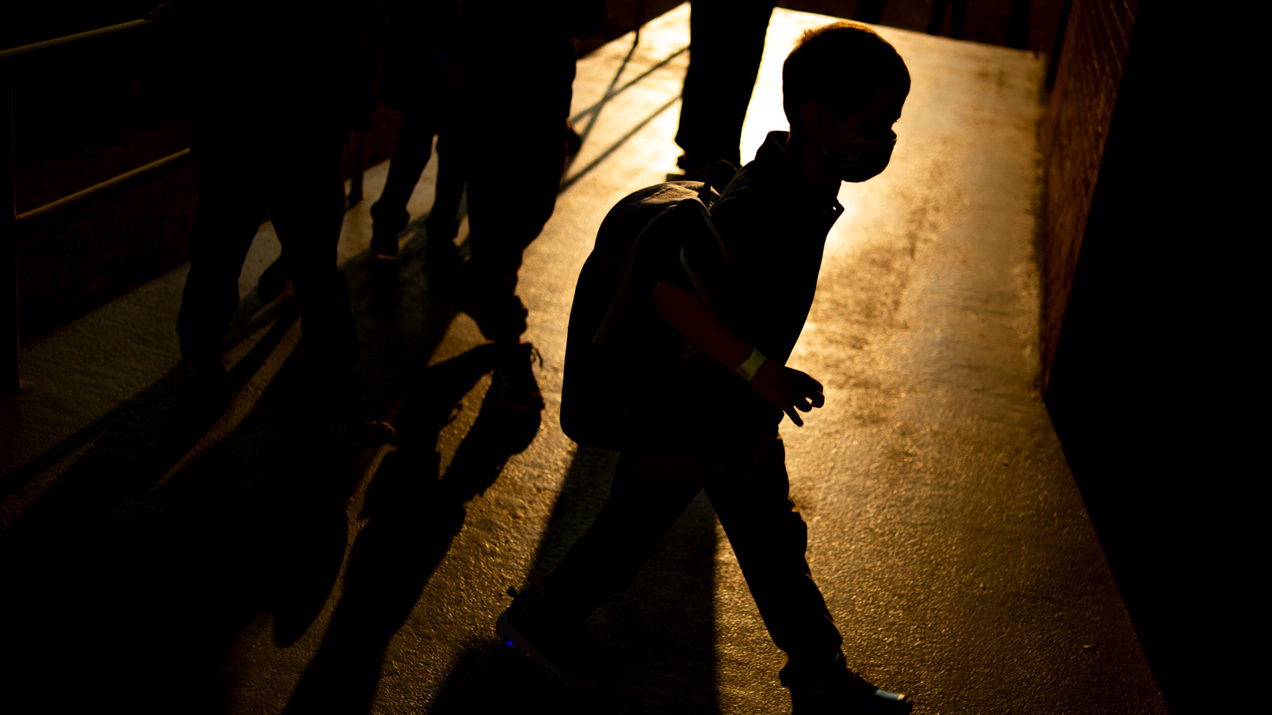 A student arrives as the sun rises during the first day of school on Aug. 4, 2021 at Freeman Elementary School in Flint, Mich. New autism numbers released Dec. 2 suggest more U.S. children are being diagnosed with the developmental condition and at younger ages. (Jake May/The Flint Journal via AP)