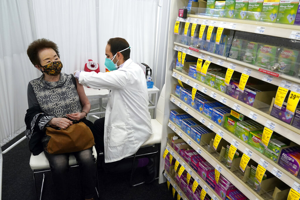 Pharmacist Todd Gharibian, right, administers a dose of the Moderna COVID-19 vaccine to Toshiko Sugiyama, left, at a CVS Pharmacy branch on March 1, 2021, in Los Angeles. (AP Photo/Marcio Jose Sanchez, File)