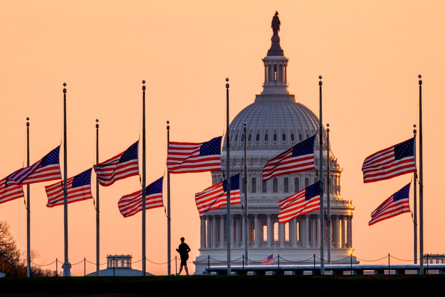 Lowered to half-staff in honor of former Senate Majority Leader Bob Dole of Kansas, flags fly in the breeze at sunrise on the National Mall with the U.S. Capitol in the background on Dec. 6, 2021, in Washington. (J. David Ake)