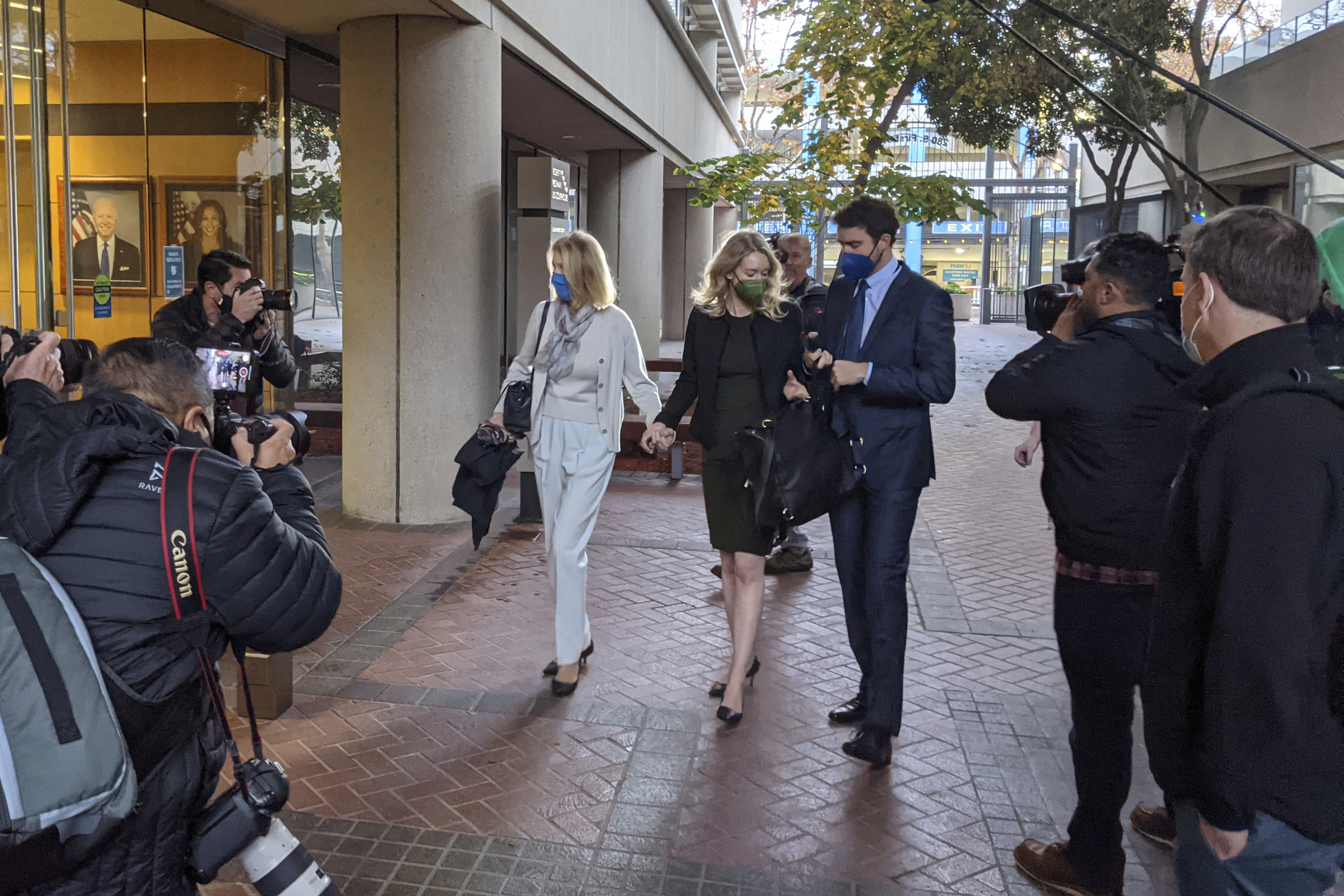 Elizabeth Holmes, center, enters the Robert F. Peckham Federal Building with her partner, Billy Evans, right, and her mother, Noel Holmes, in San Jose, Calif., on Dec. 7, 2021. Looking on at far right is John Carreyrou, the former Wall Street Journal reporter who wrote the October 2015 story that exposed flaws in Theranos' blood-testing technology. (AP Photo/Michael Liedtke)