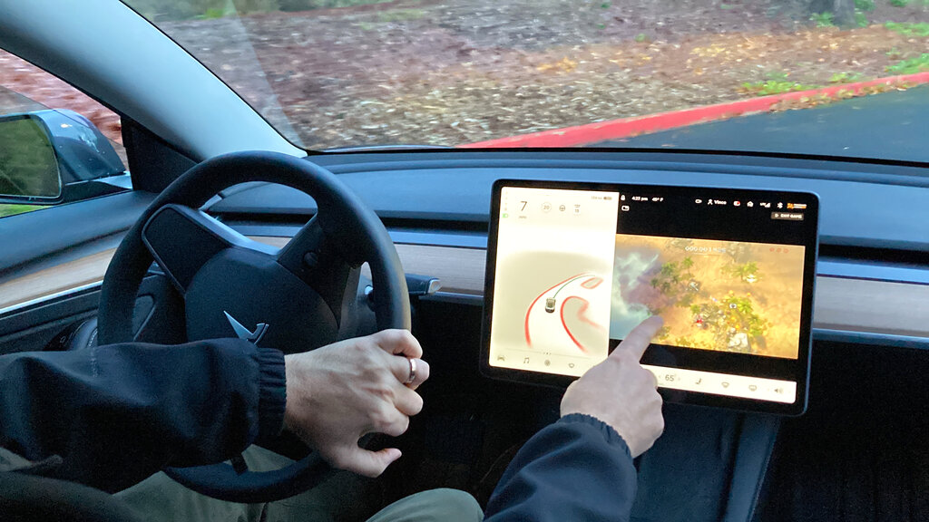 Vince Patton, a new Tesla owner, demonstrates on Wednesday, Dec. 8, 2021, on a closed course in Portland, Ore., how he can play video games on the vehicle's console while driving. (AP Photo/Gillian Flaccus)